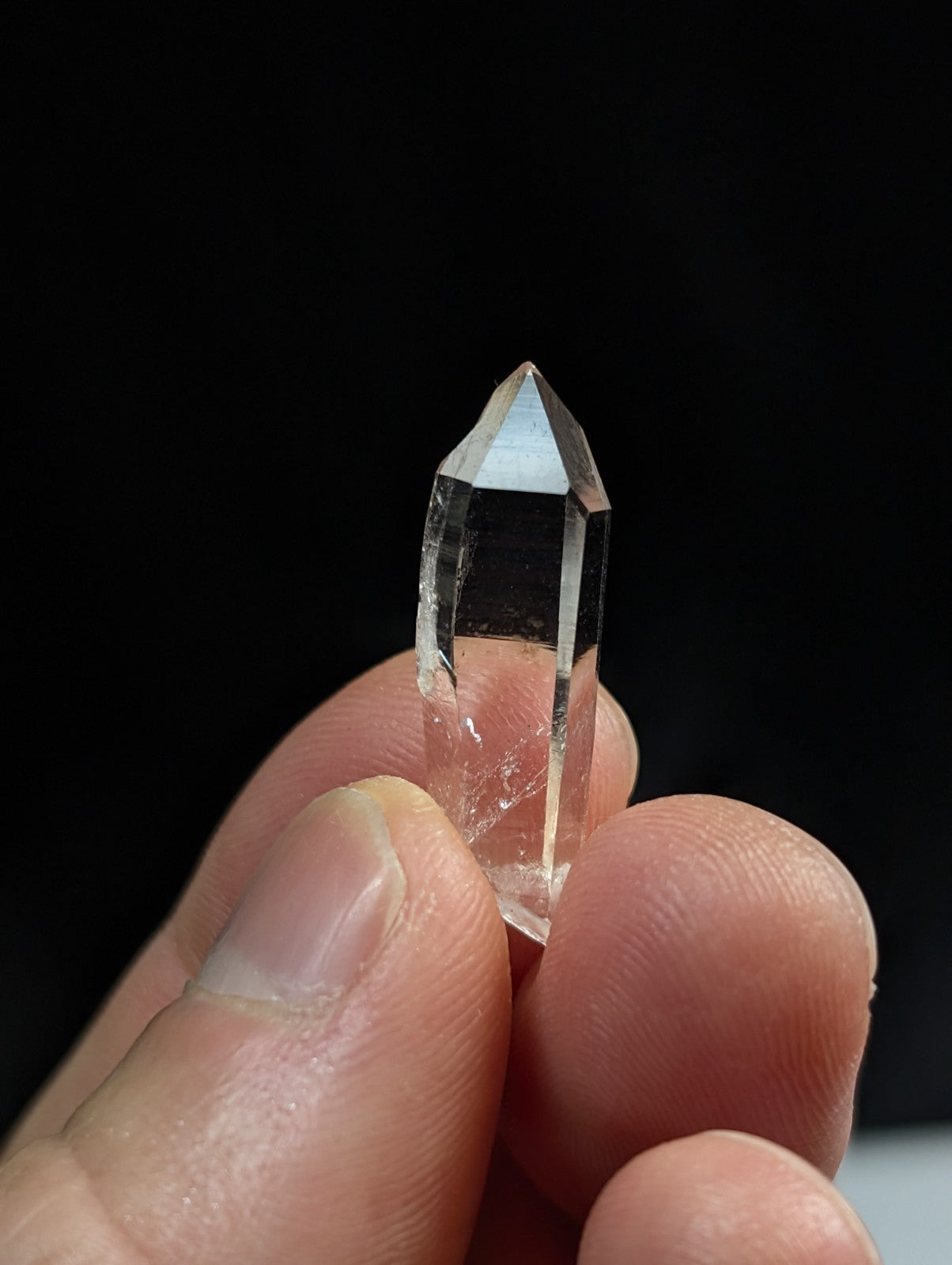 A clear, transparent quartz crystal with a pointed tip and faceted sides.