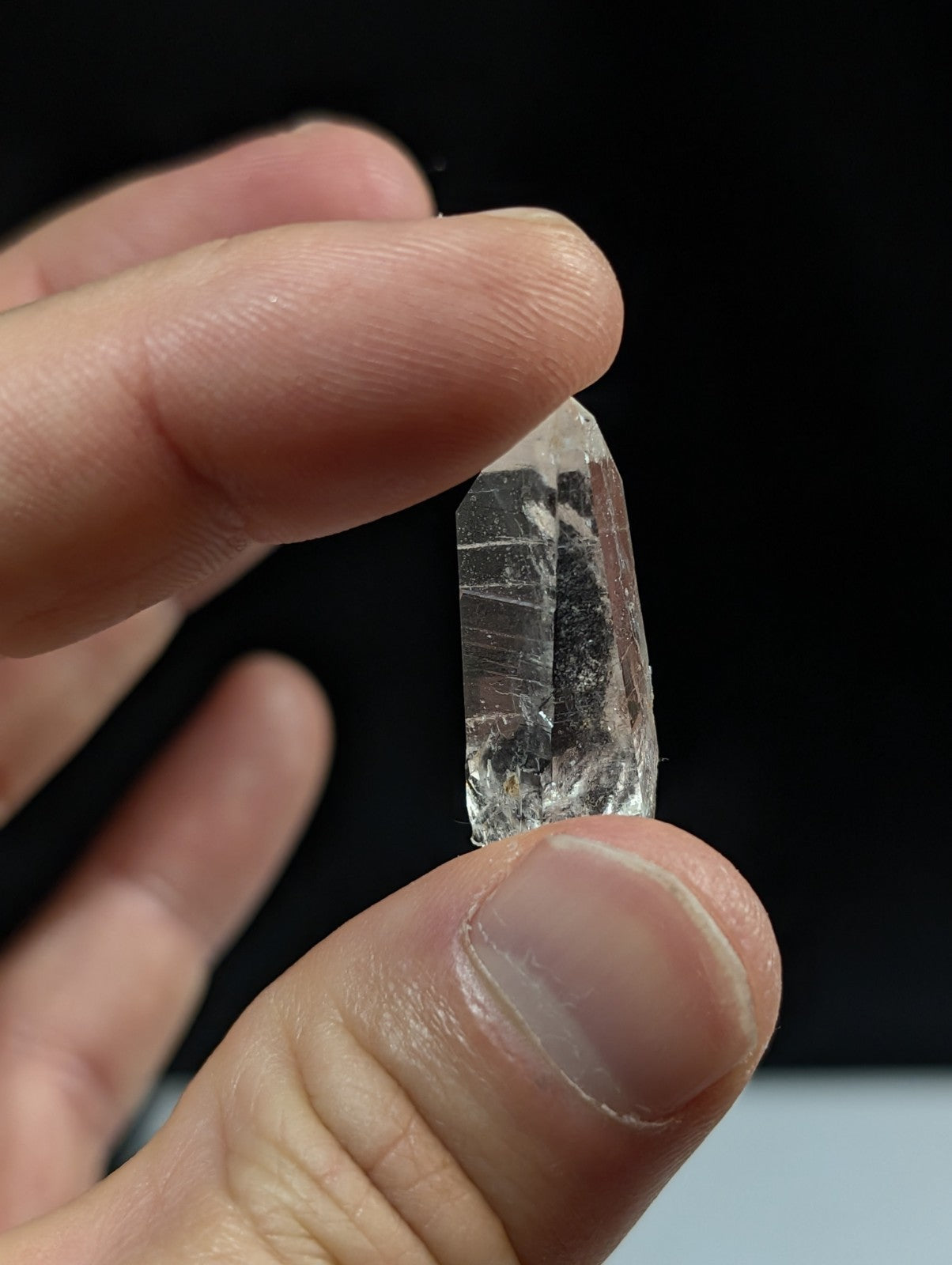 A clear, translucent quartz crystal with visible internal striations and a pointed tip.