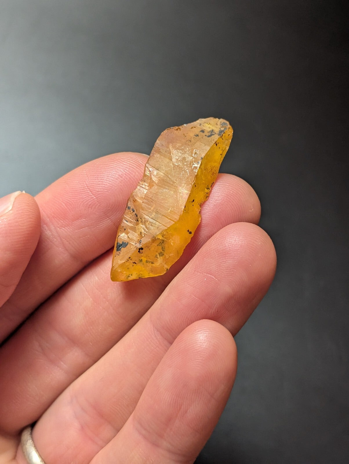 A translucent amber-colored crystal with a smooth, slightly jagged surface and subtle internal inclusions.