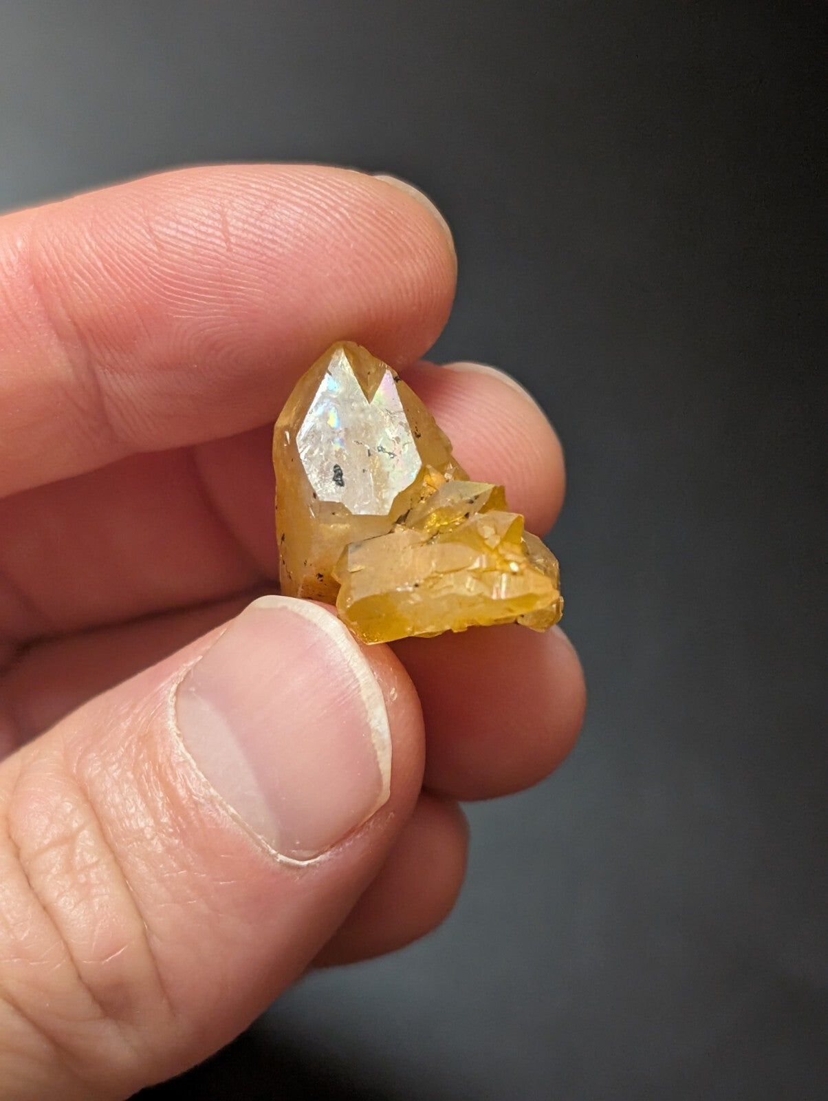 A translucent yellow crystal with a faceted, pointed top and rougher base.