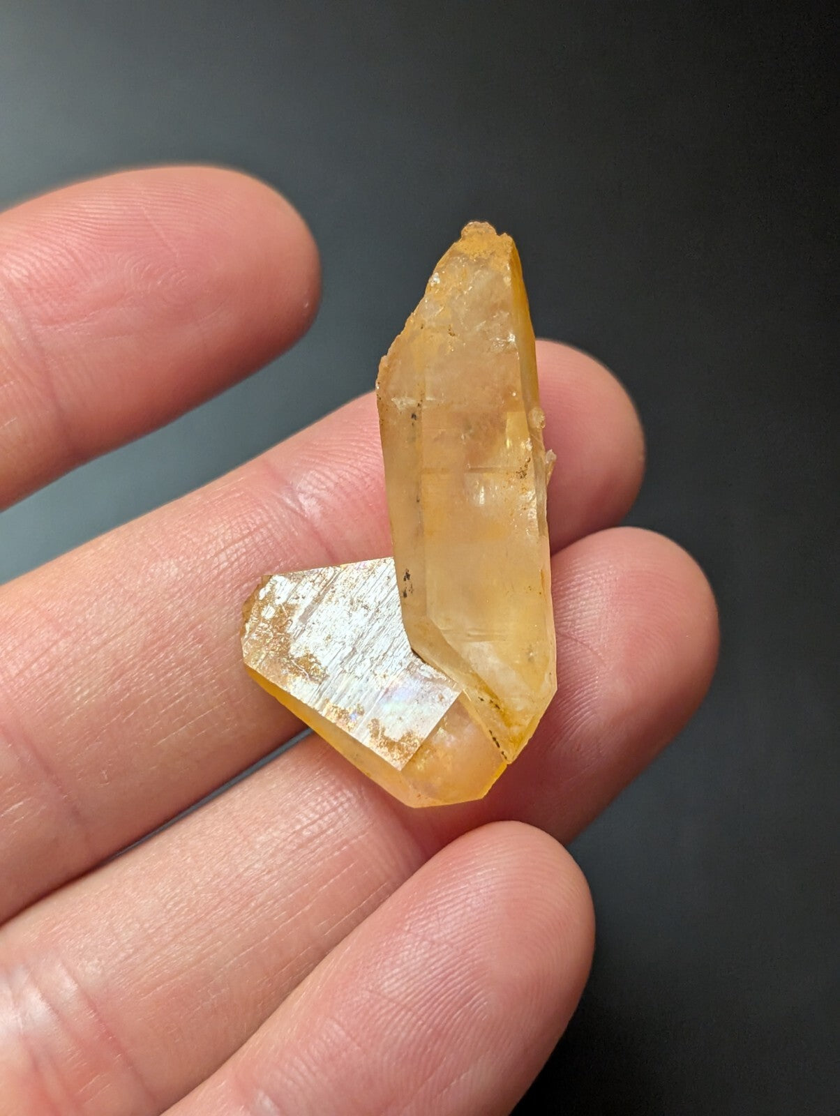 A translucent amber-colored crystal with a pointed, faceted top and a flat base.