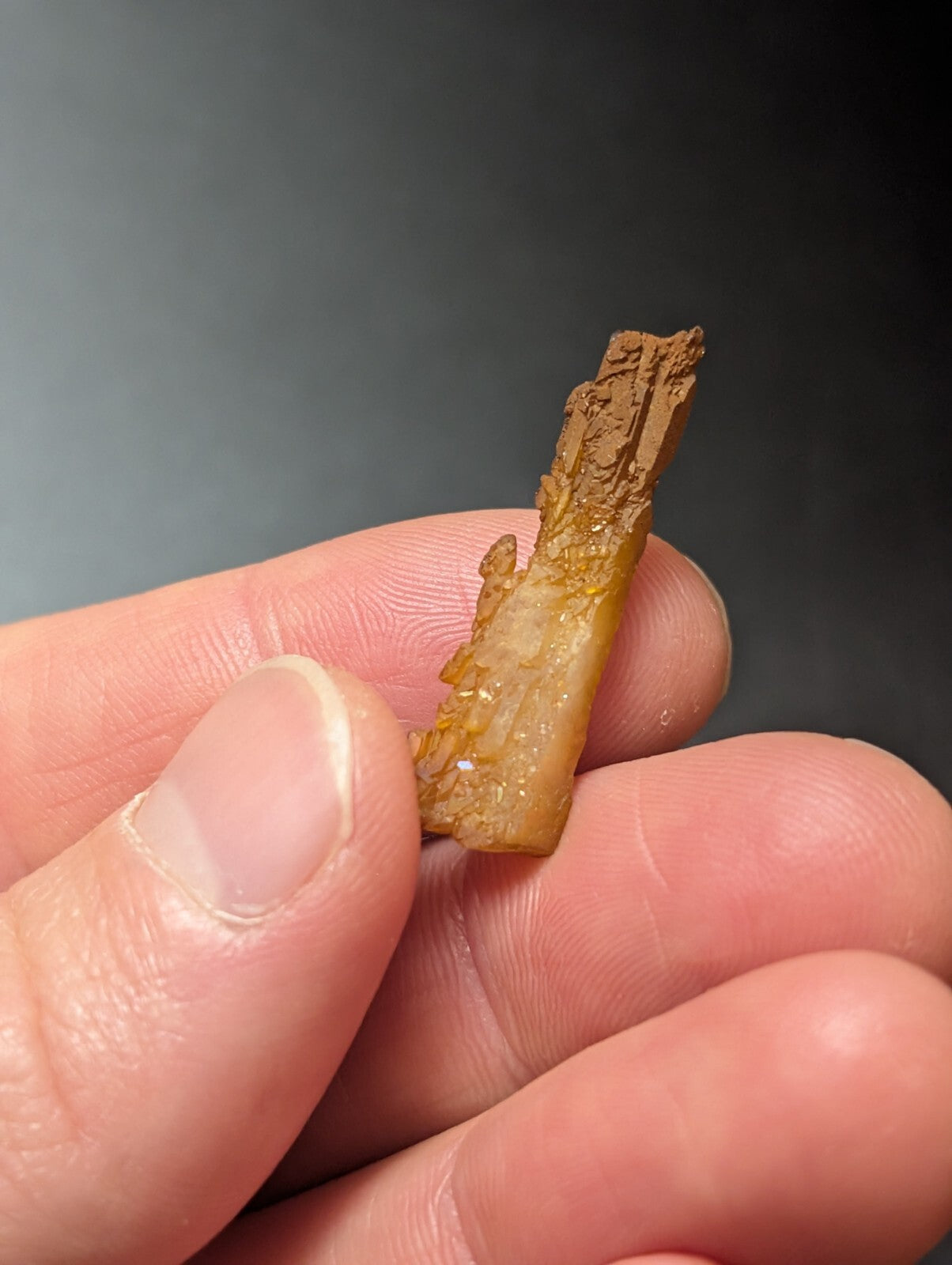 A translucent amber-colored mineral specimen with a rough, crystalline texture and brownish surface.