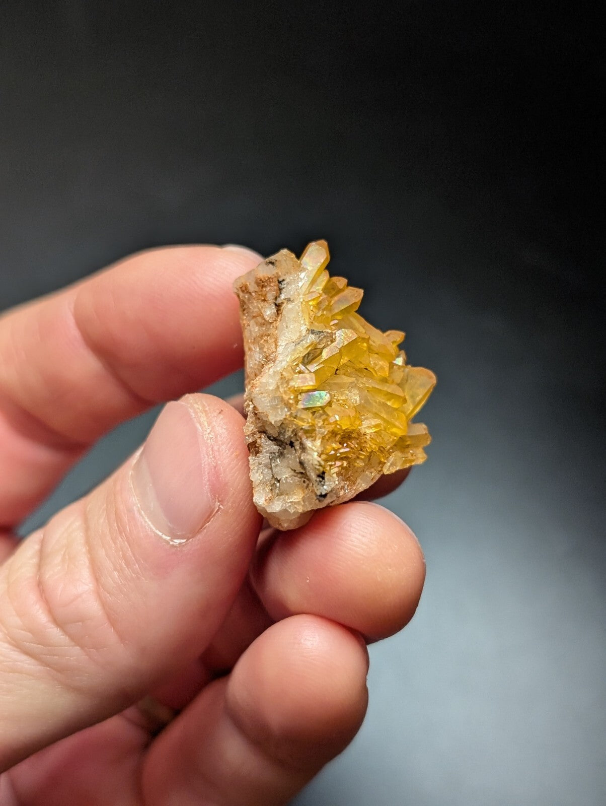 A cluster of translucent golden-yellow crystals with a rough, earthy base.