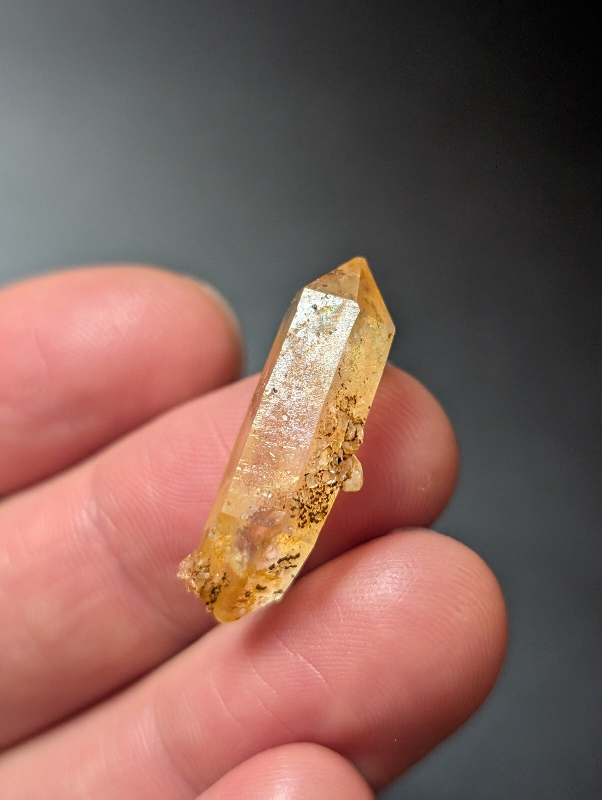 A translucent golden-yellow crystal with natural inclusions and a pointed, faceted tip.