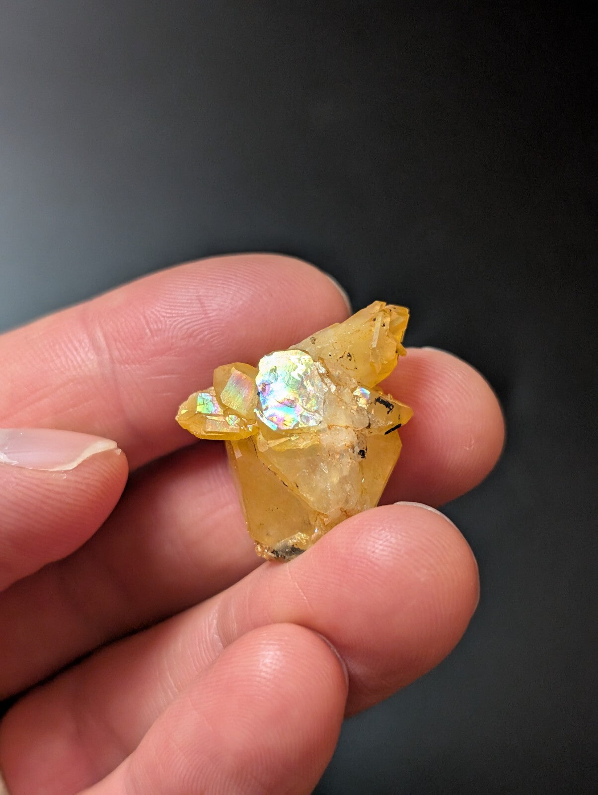 A translucent yellow crystal cluster with a central iridescent, rainbow-hued inclusion.