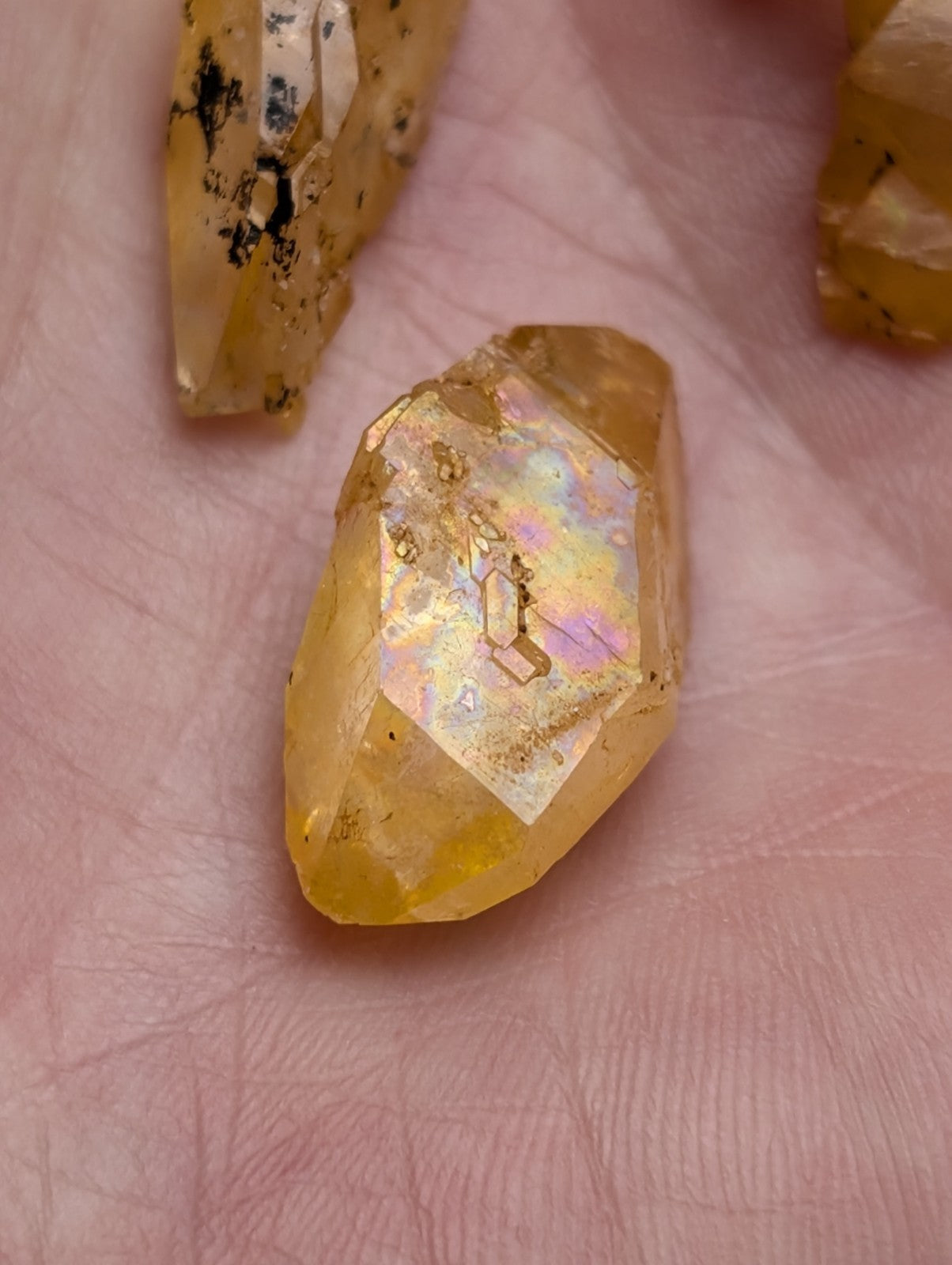 A golden-yellow faceted citrine crystal with natural inclusions and iridescent rainbow hues from arkansas quartz set