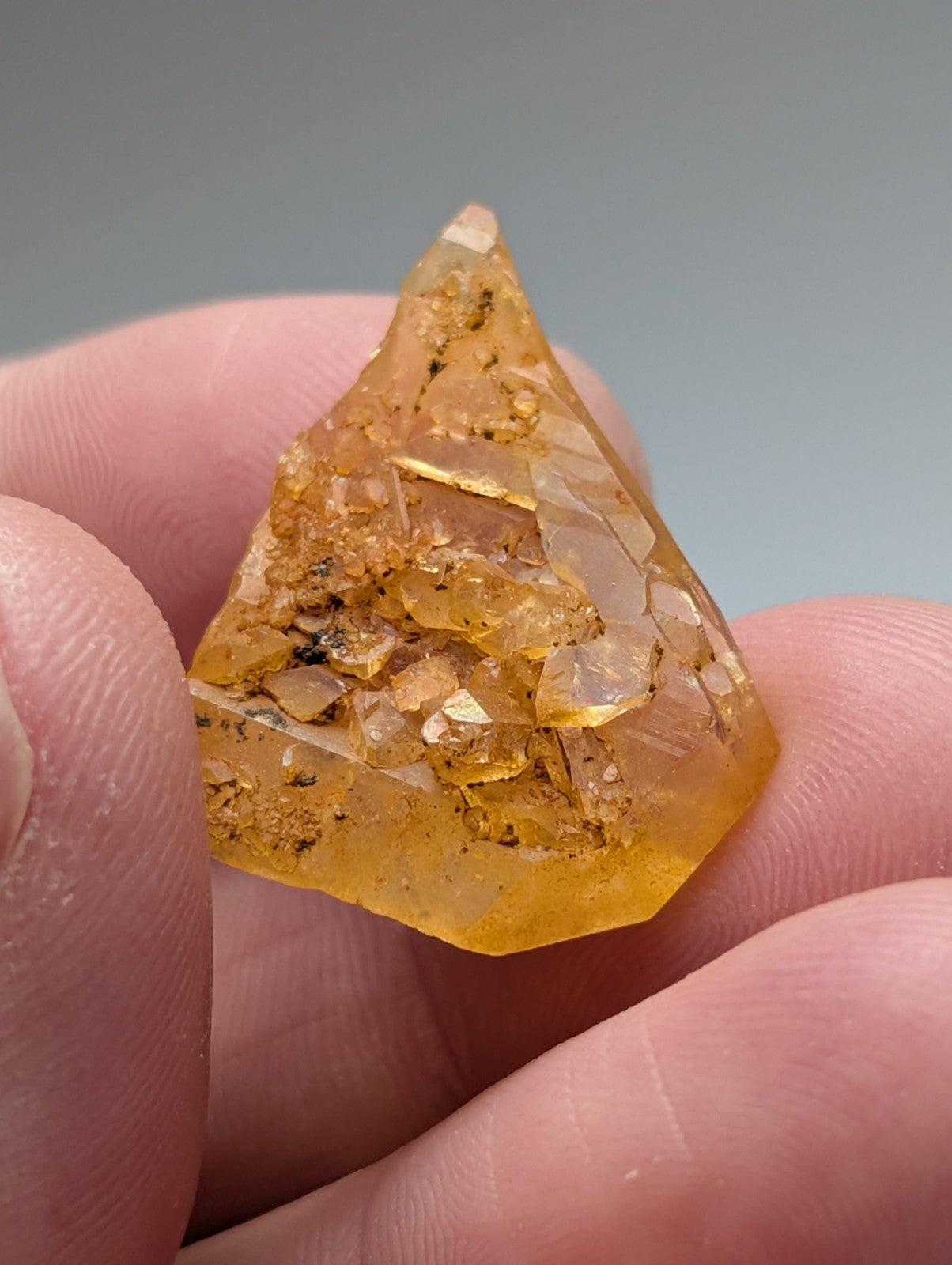 A translucent golden-yellow arkansas quartz crystal with natural iridescence and embedded smaller crystals