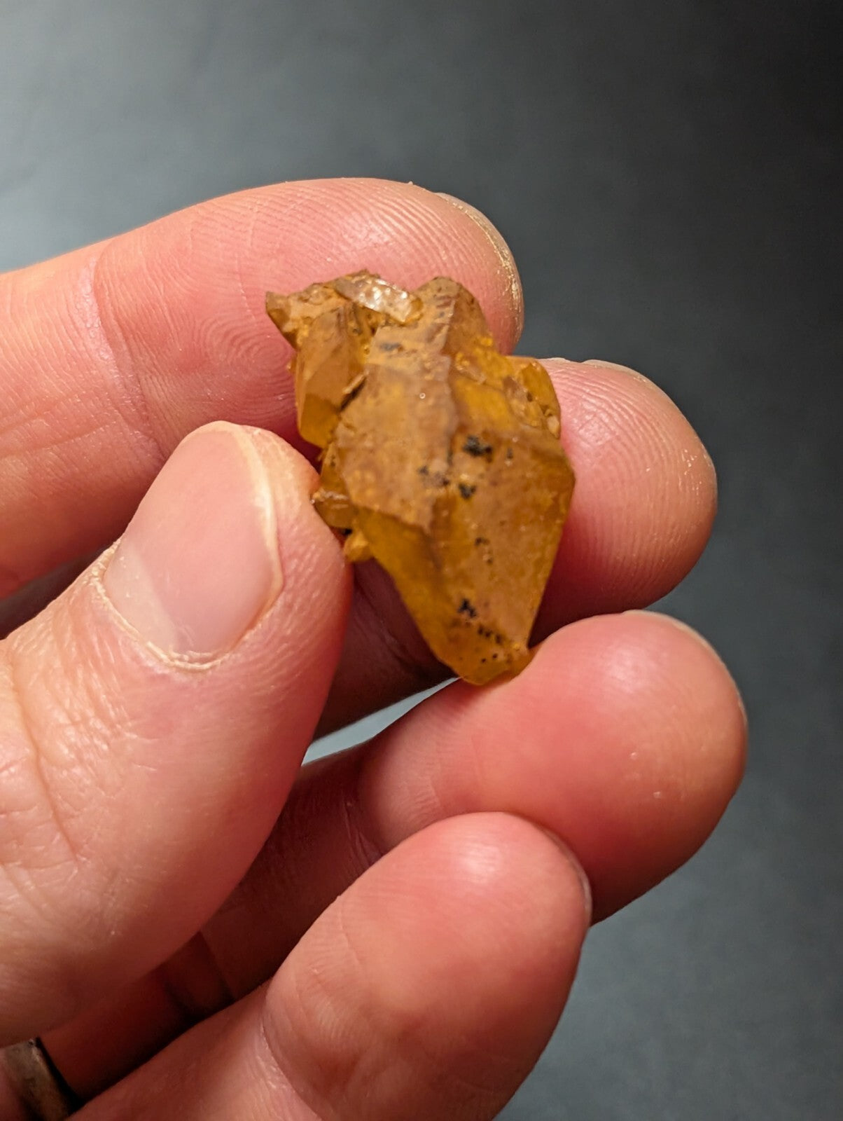 A translucent amber-colored, irregularly shaped mineral specimen with visible internal inclusions and a rough, natural surface.