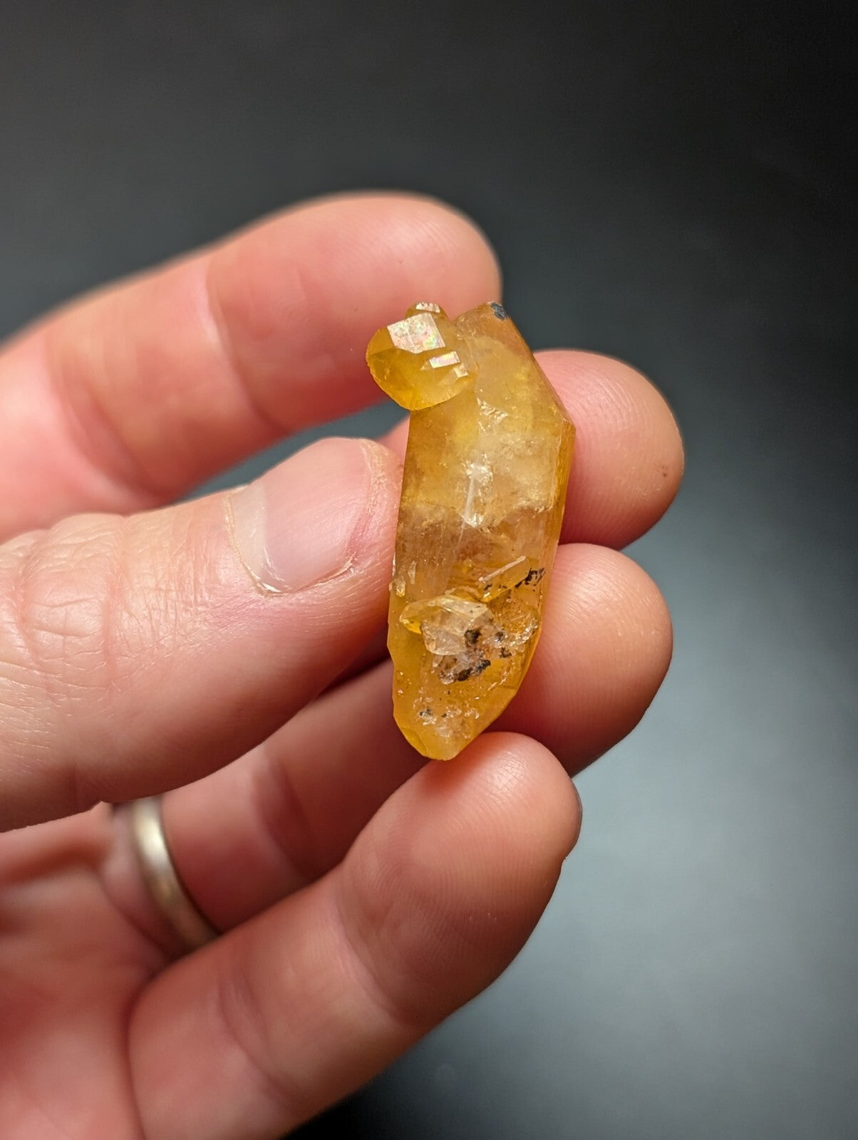 A translucent golden-yellow citrine crystal with a faceted, elongated shape and natural inclusions.