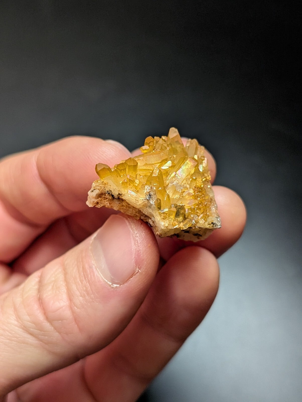 A cluster of translucent golden-yellow crystals with sharp, faceted edges and a rough, earthy base.
