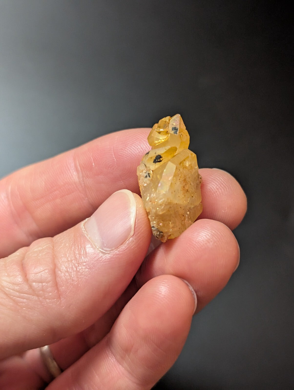 A translucent yellow crystal with a rough, faceted surface and small dark inclusions.