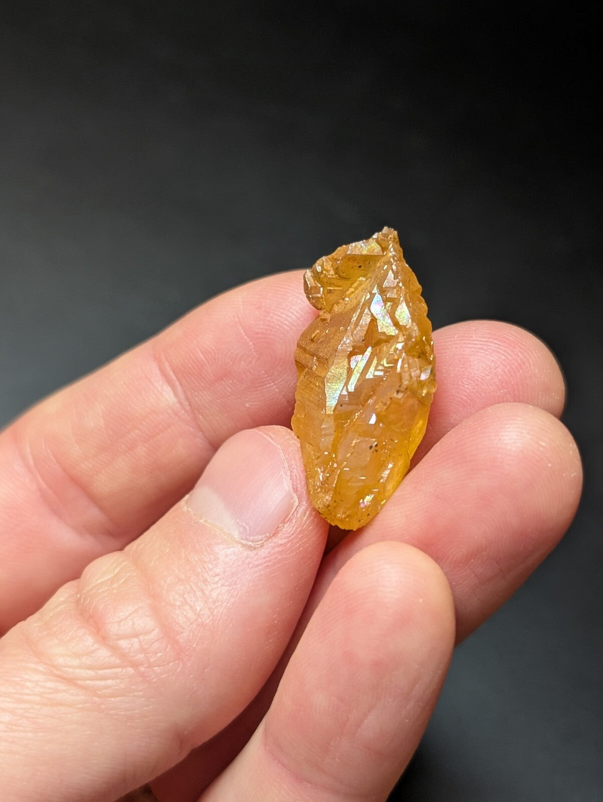 A translucent golden-yellow crystal with a rough, jagged surface and visible internal facets.