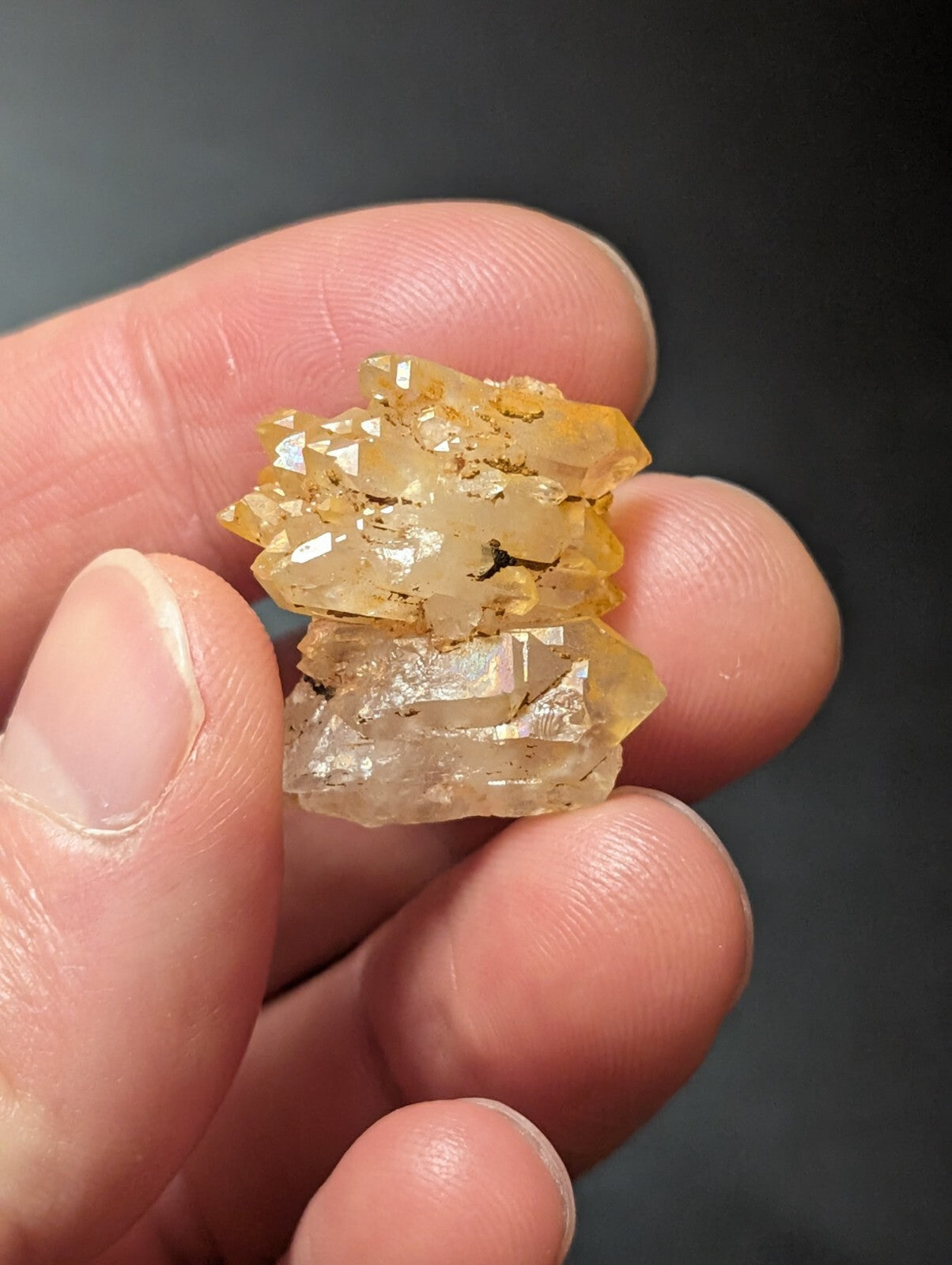 A cluster of translucent yellow and clear quartz crystals held in a hand.