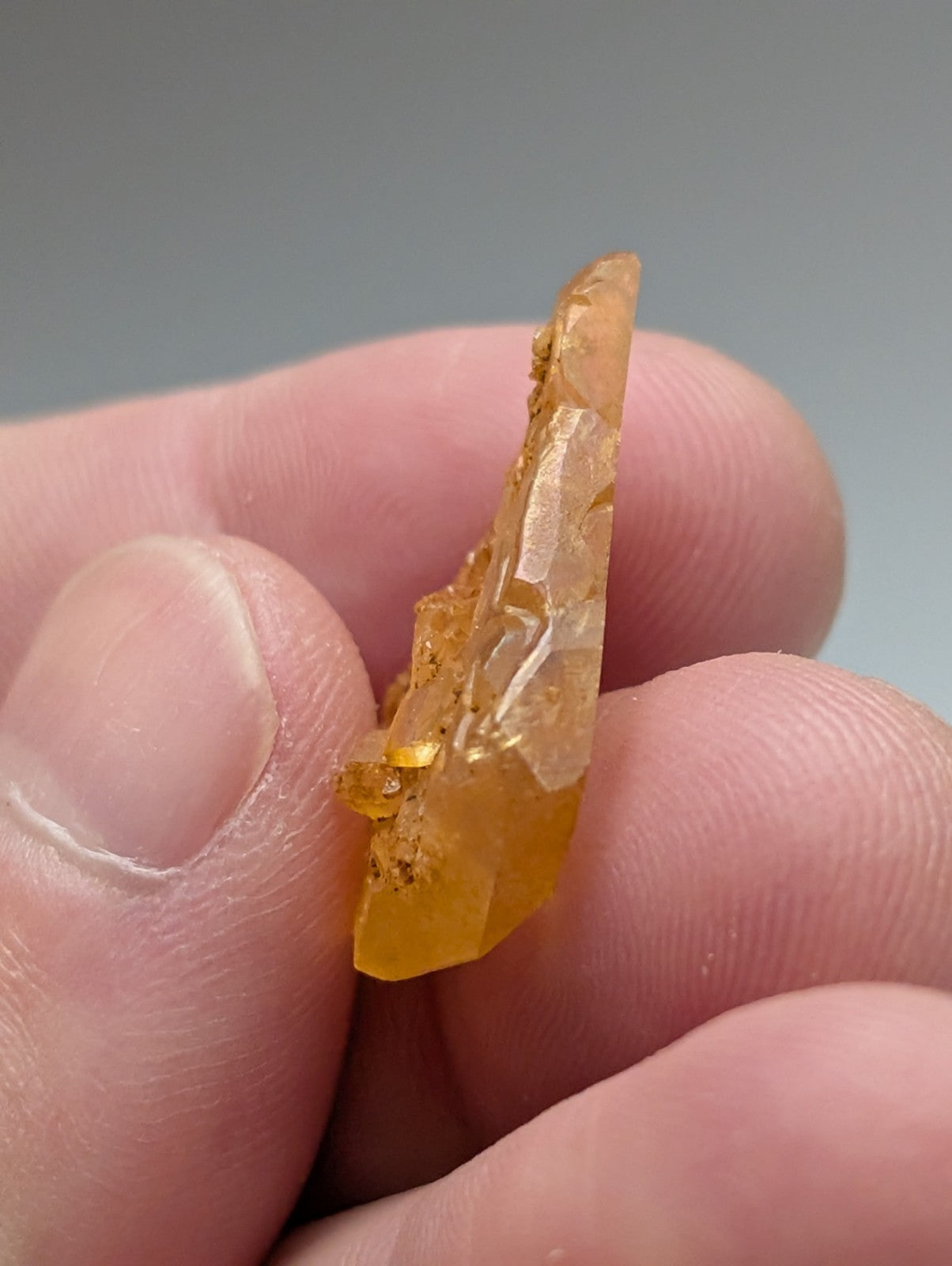A translucent amber arkansas quartz crystal with jagged surface and golden inclusions from a unique set of 3