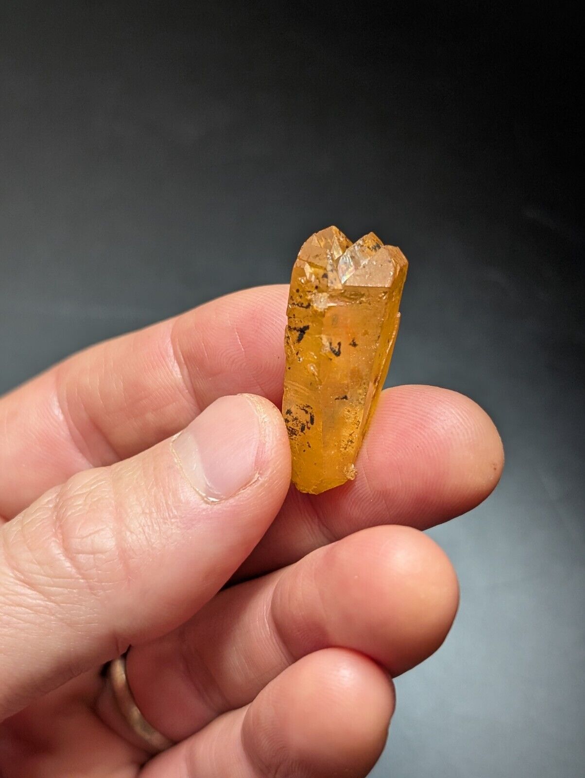 Translucent orange crystal held in hand.