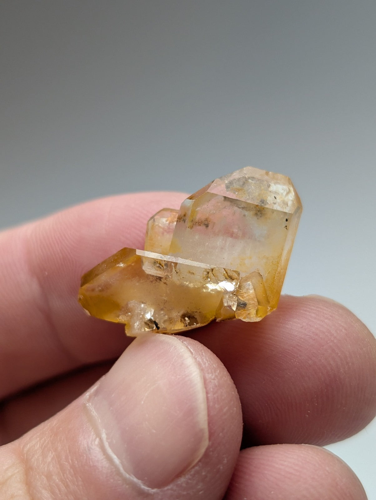 A translucent yellow orange arkansas quartz crystal cluster with natural iridescence and visible internal inclusions