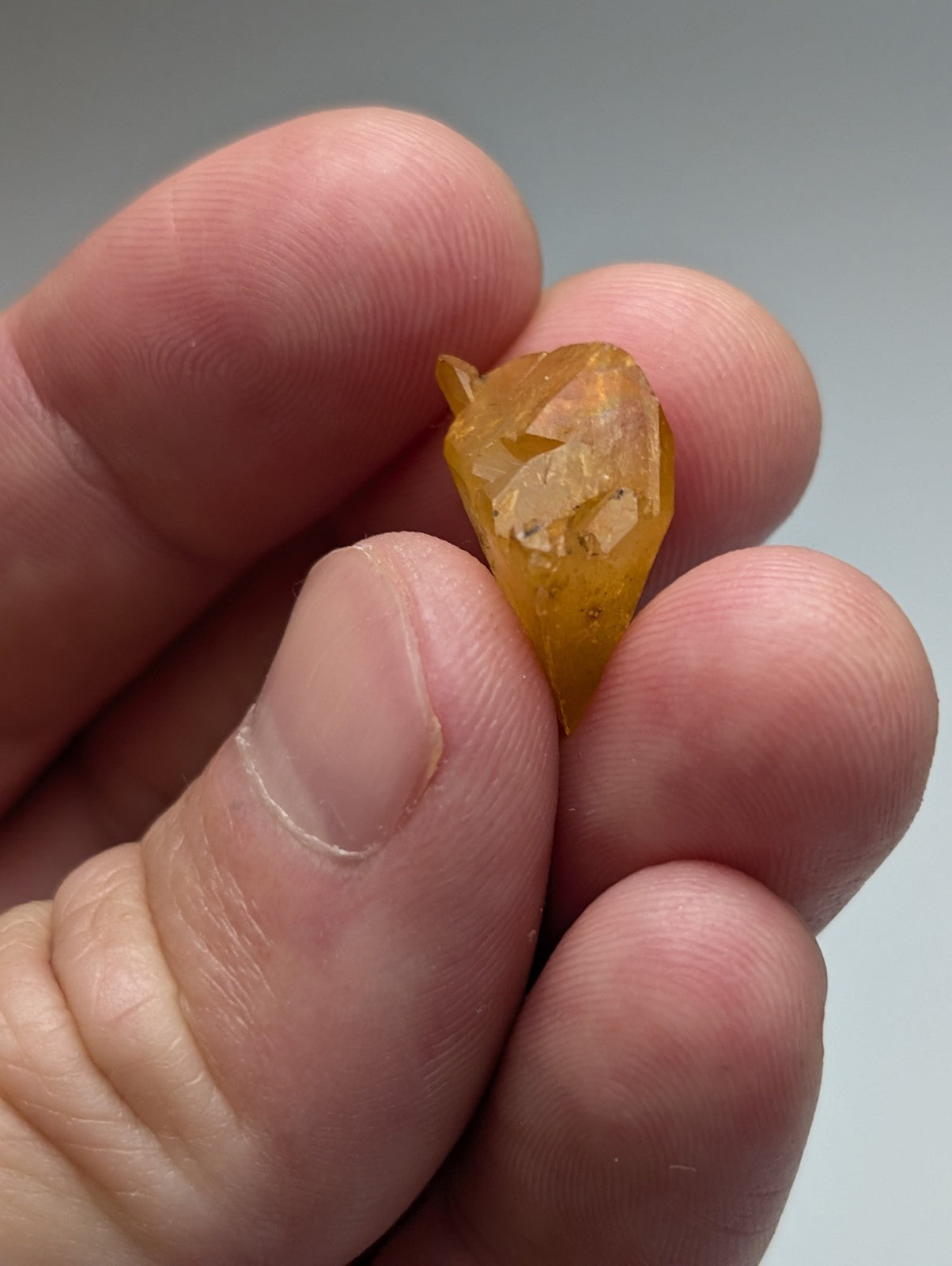 A translucent golden-yellow citrine crystal with a faceted pointed tip and visible internal inclusions from arkansas quartz set