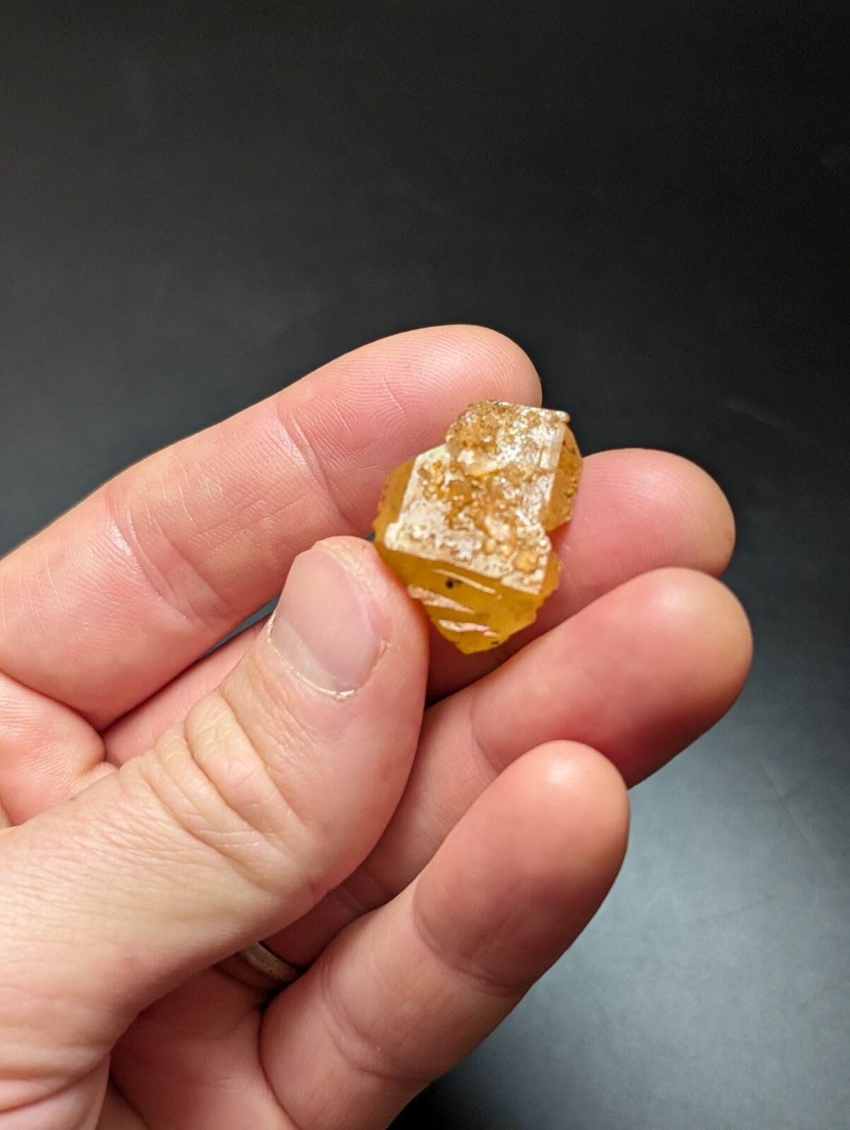 A rough, translucent yellow-orange gemstone with visible crystalline facets and internal inclusions.