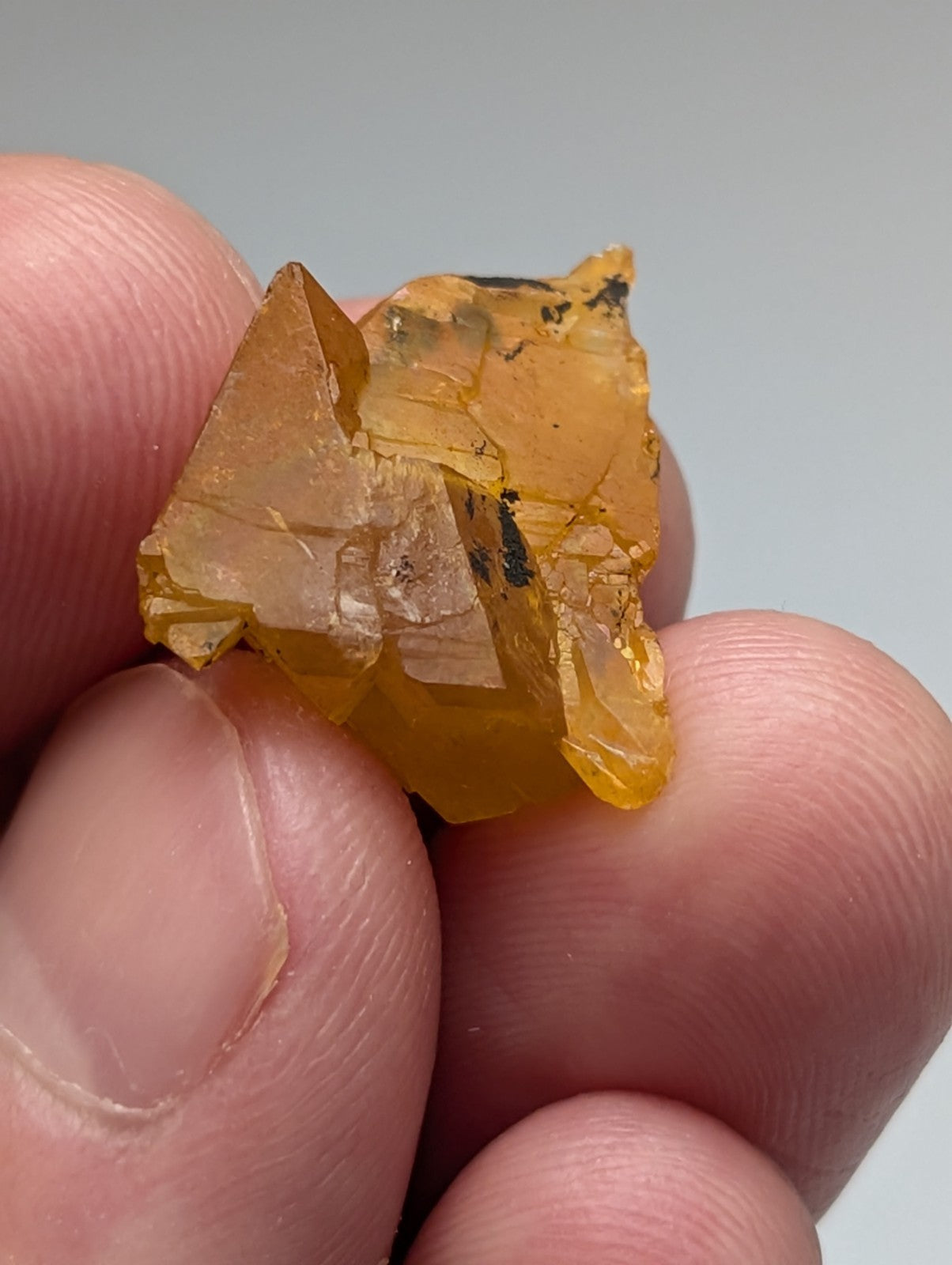 A translucent amber arkansas quartz crystal with jagged faceted edges and natural iridescence in a set of 3