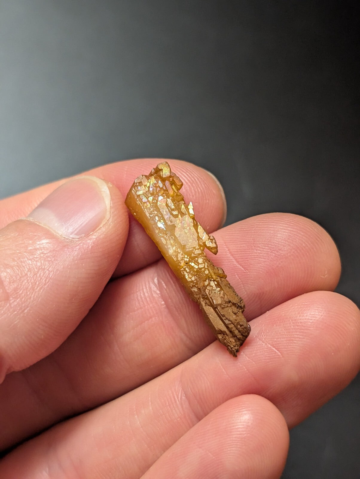 A golden, translucent crystal fragment with a rough, jagged surface and natural striations.
