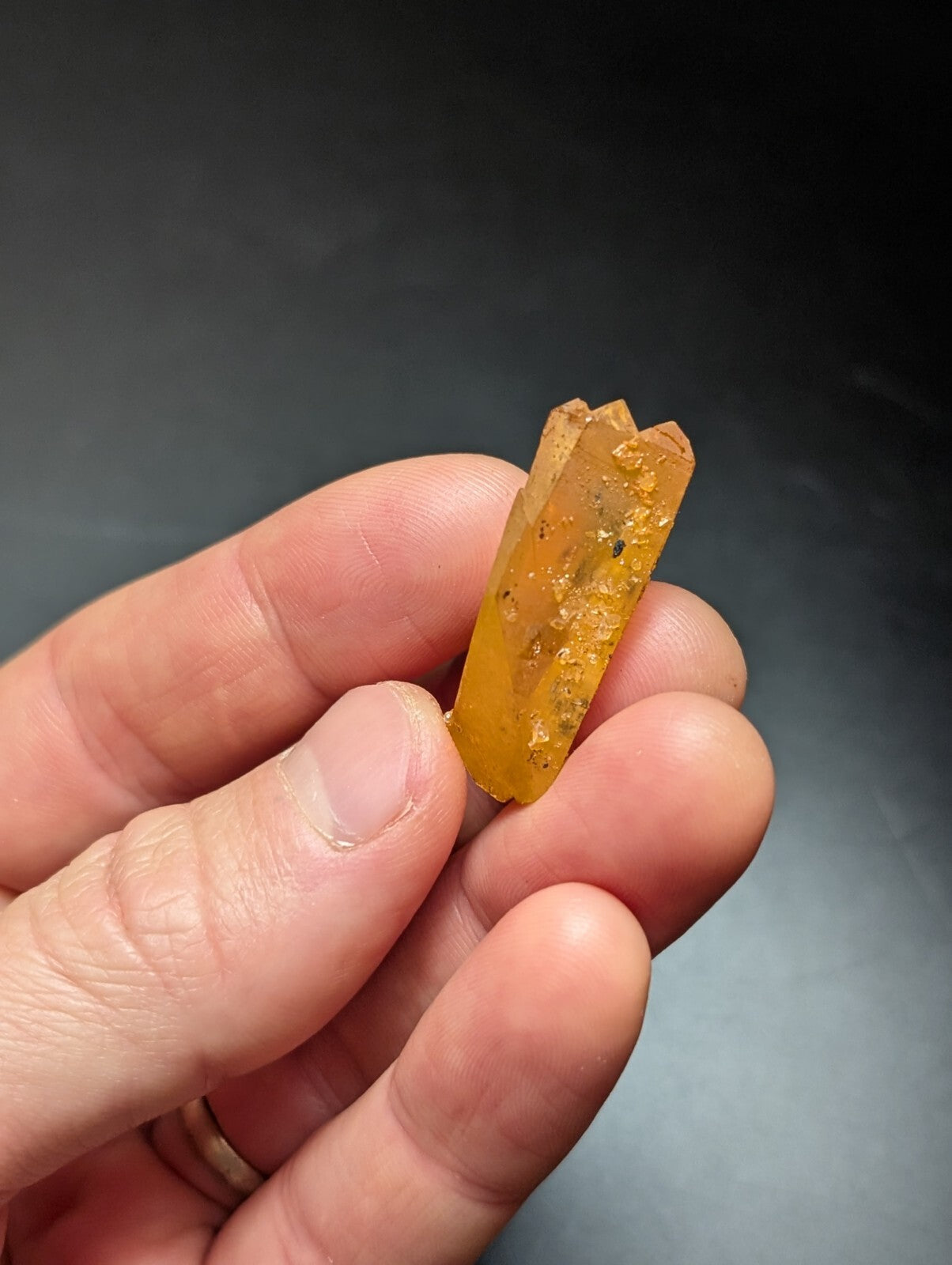A translucent amber-colored crystal with a rough, faceted surface and visible internal inclusions.