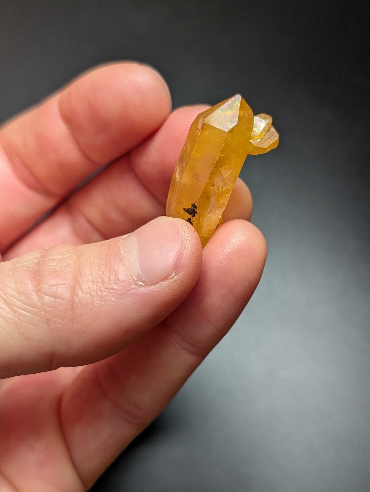 A translucent golden-yellow citrine crystal with a pointed, faceted top and natural inclusions.