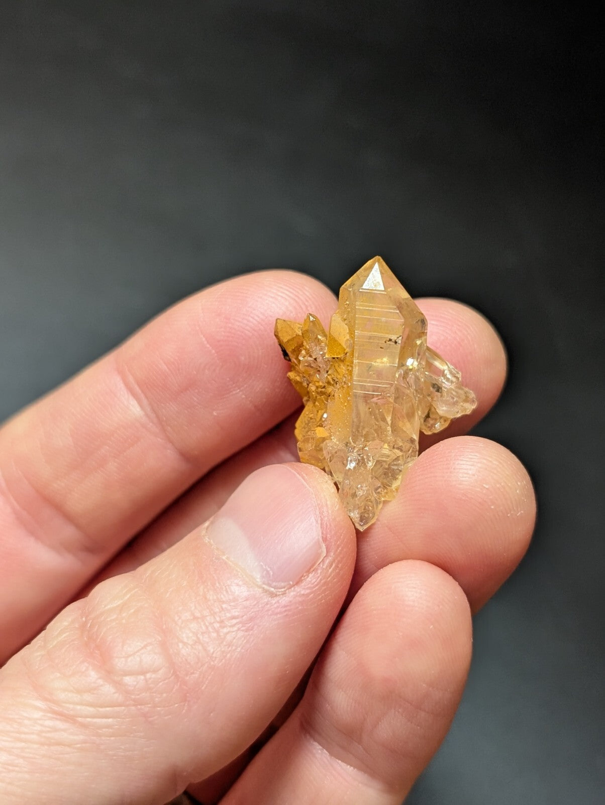 A translucent golden-yellow crystal cluster with a pointed, faceted central spike and smaller branching crystals.