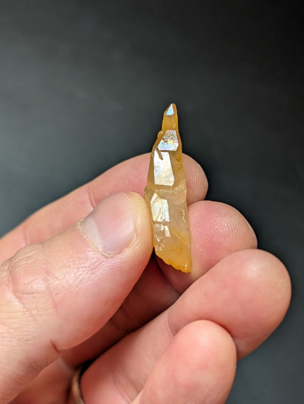 A translucent amber-colored quartz crystal with a pointed tip and reflective facets.