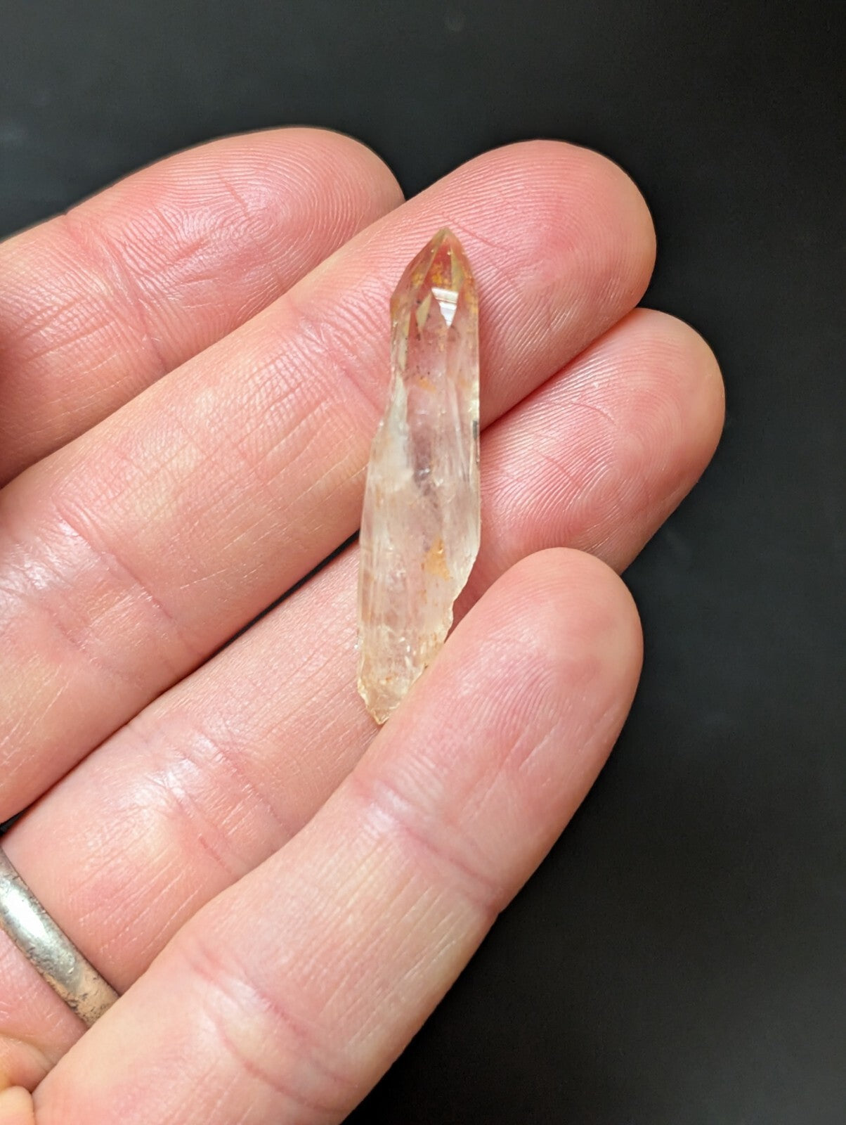 A translucent, amber-hued quartz crystal with a pointed tip and natural facets.