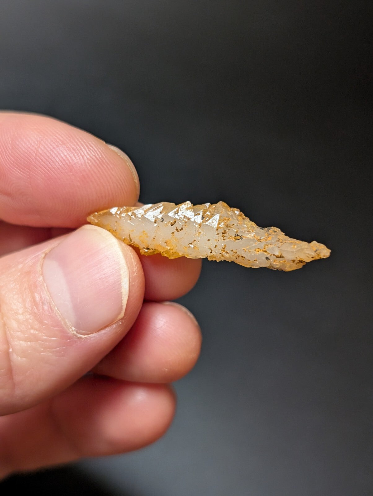 A translucent, amber-hued crystal shard with a jagged, naturally formed edge and subtle internal inclusions.