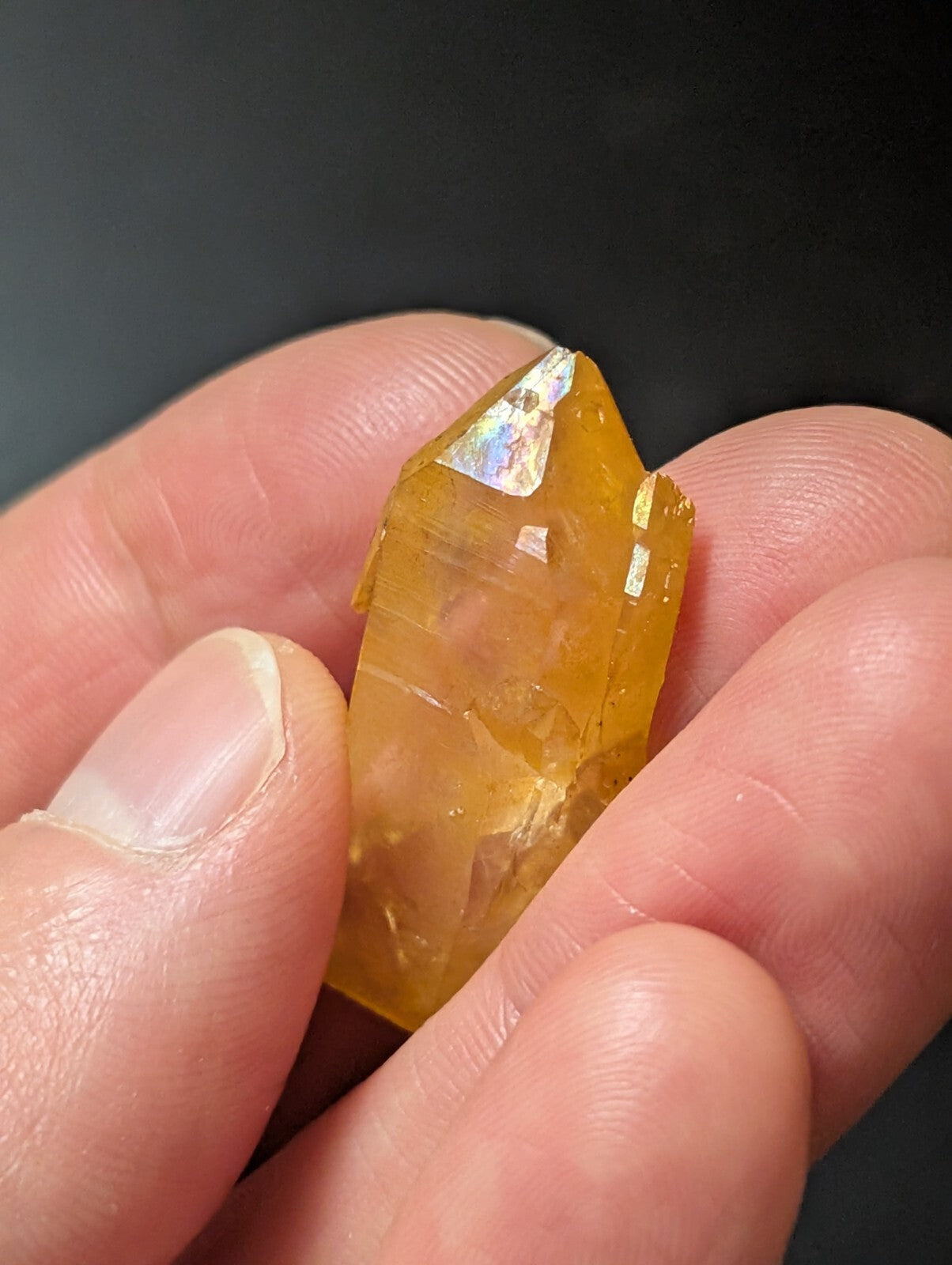 A translucent golden-yellow citrine crystal with a pointed, faceted top and natural mineral inclusions.