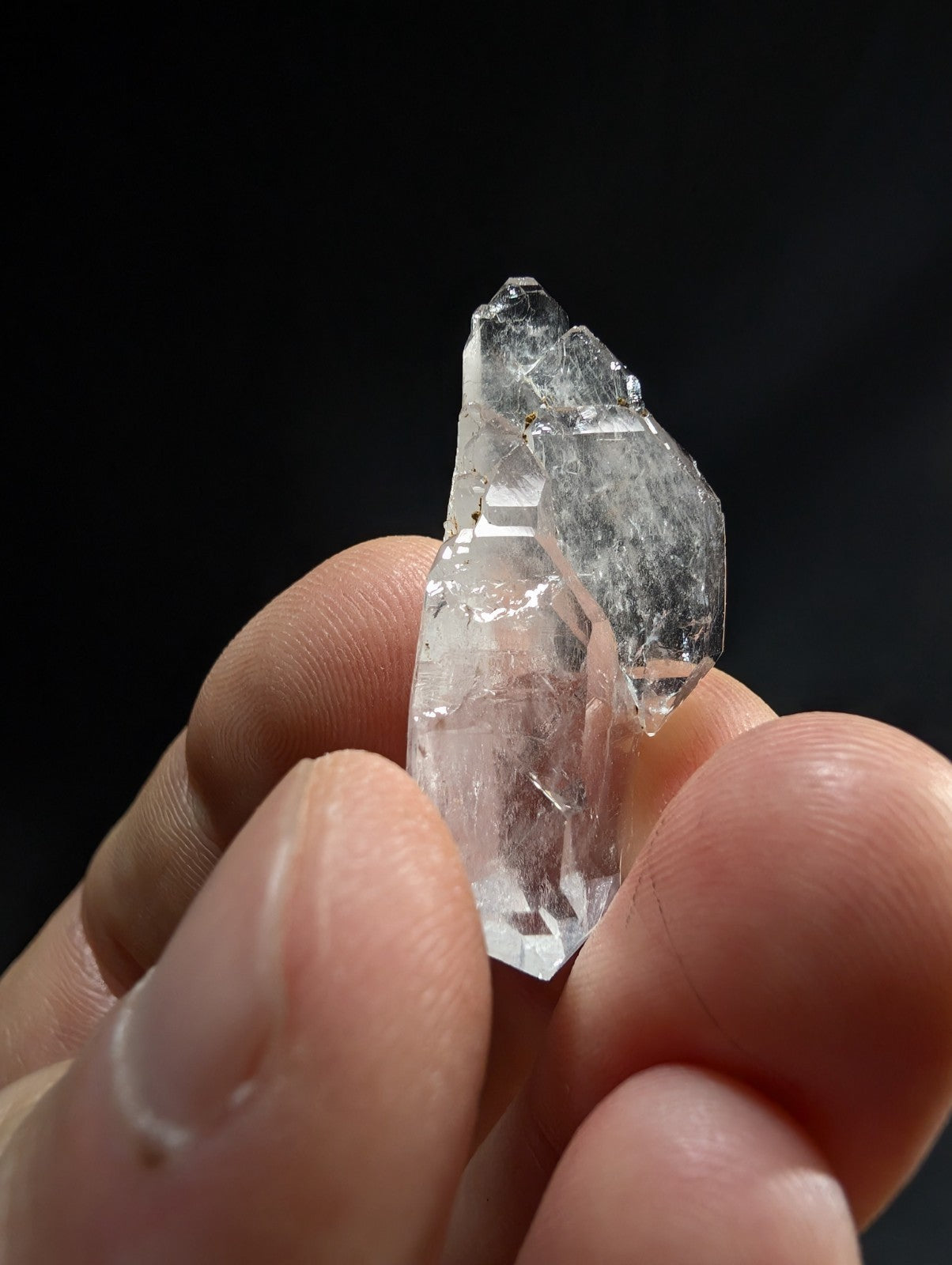 A translucent, clear quartz crystal with a faceted and slightly rough surface.