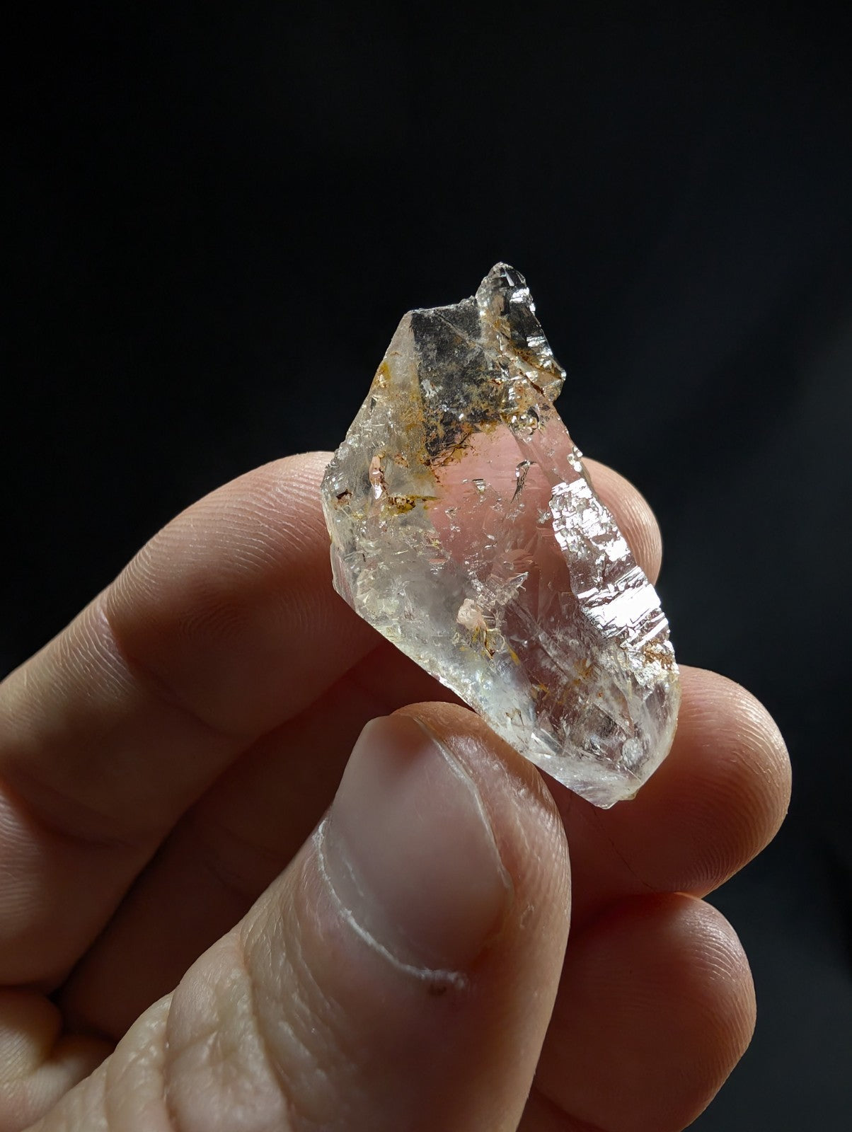 A translucent, clear quartz crystal with natural facets and subtle golden inclusions.