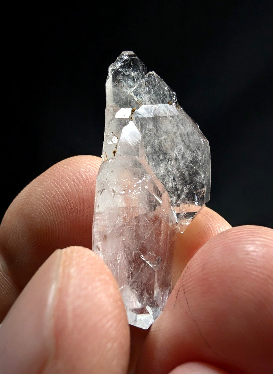 A translucent, clear quartz crystal with a faceted and jagged surface.