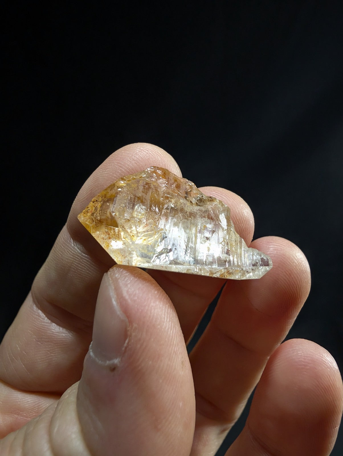 A translucent golden-yellow crystal with visible internal striations and a rough, natural edge.