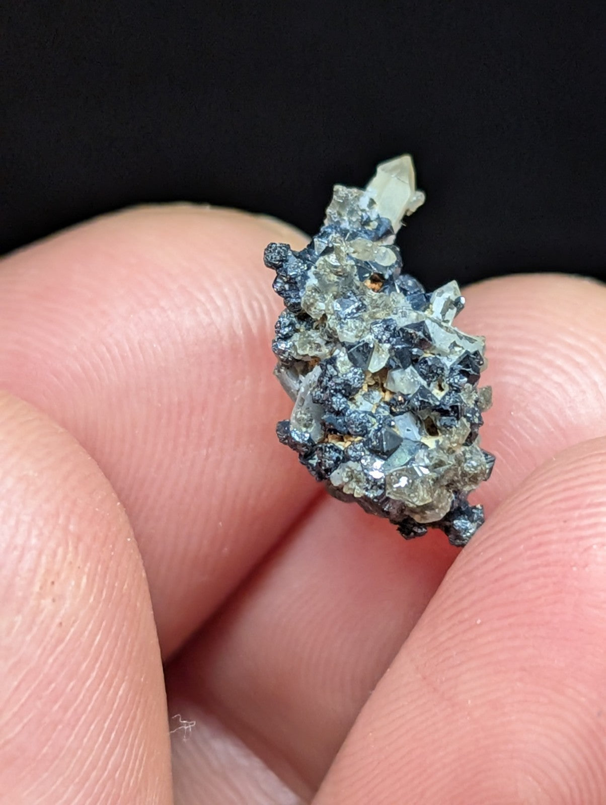A cluster of translucent, grayish-blue crystals with sharp facets and a rough, dark matrix holding them together.