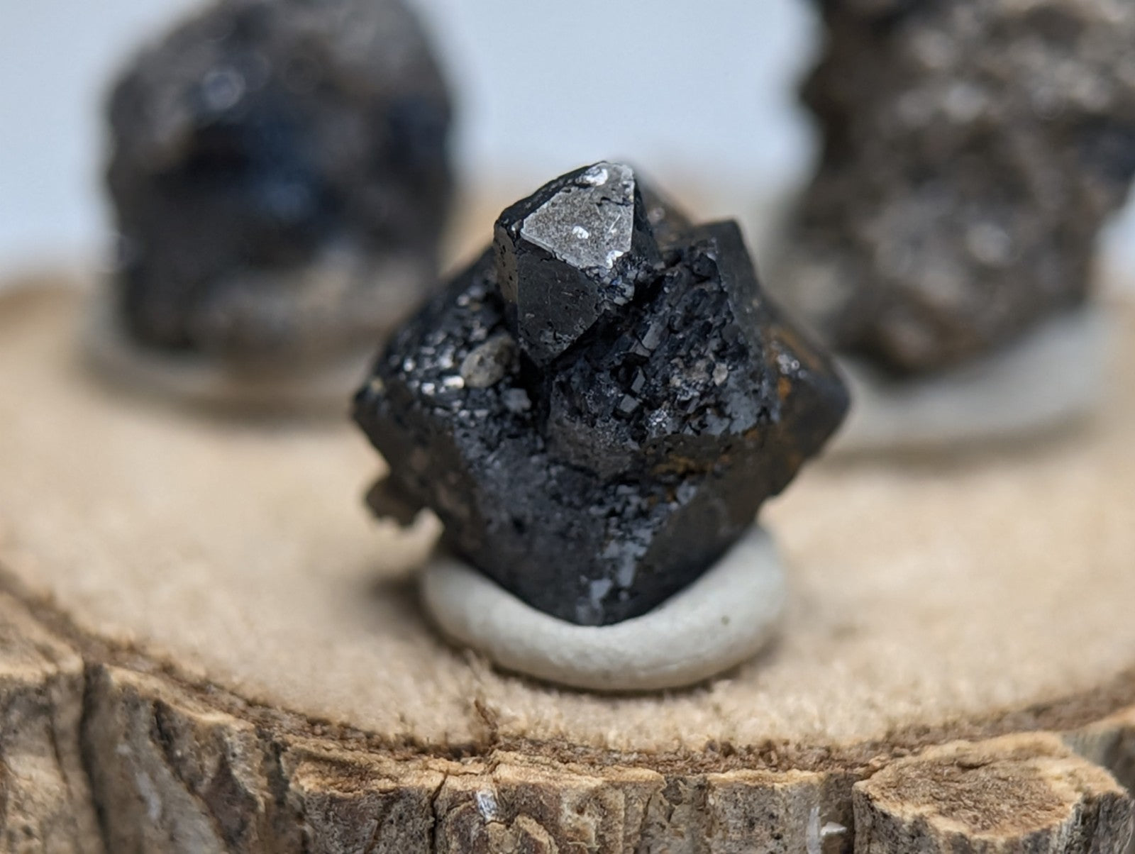 Set of 3 brookite and smoky quartz dark faceted mineral specimens with metallic sheen on wood stand from Arkansas