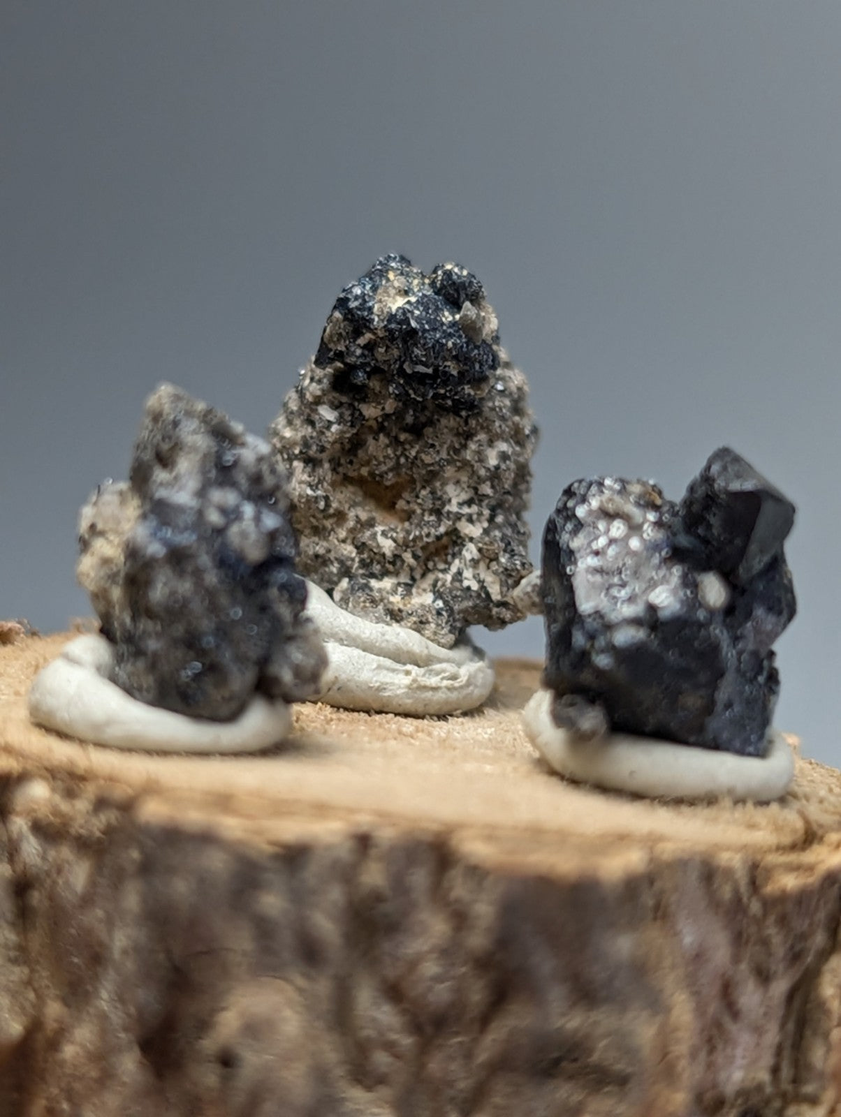 Set of 3 brookite and smoky quartz dark mineral rocks with metallic sheen on rustic wooden stand from magnet cove arkansas