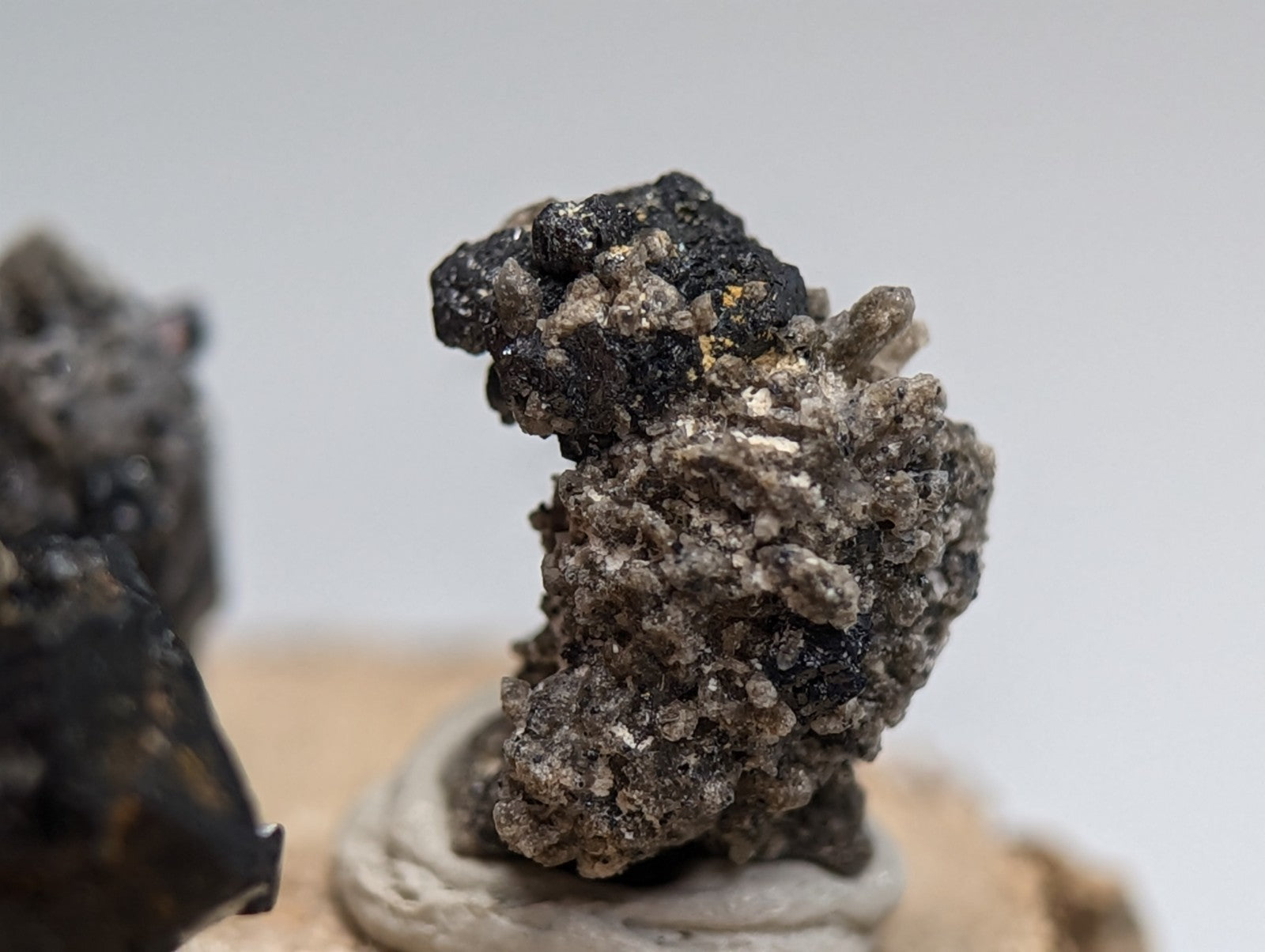 Set of 3 brookite and smoky quartz mineral specimens with black and gray textured surfaces on a wood stand from Arkansas