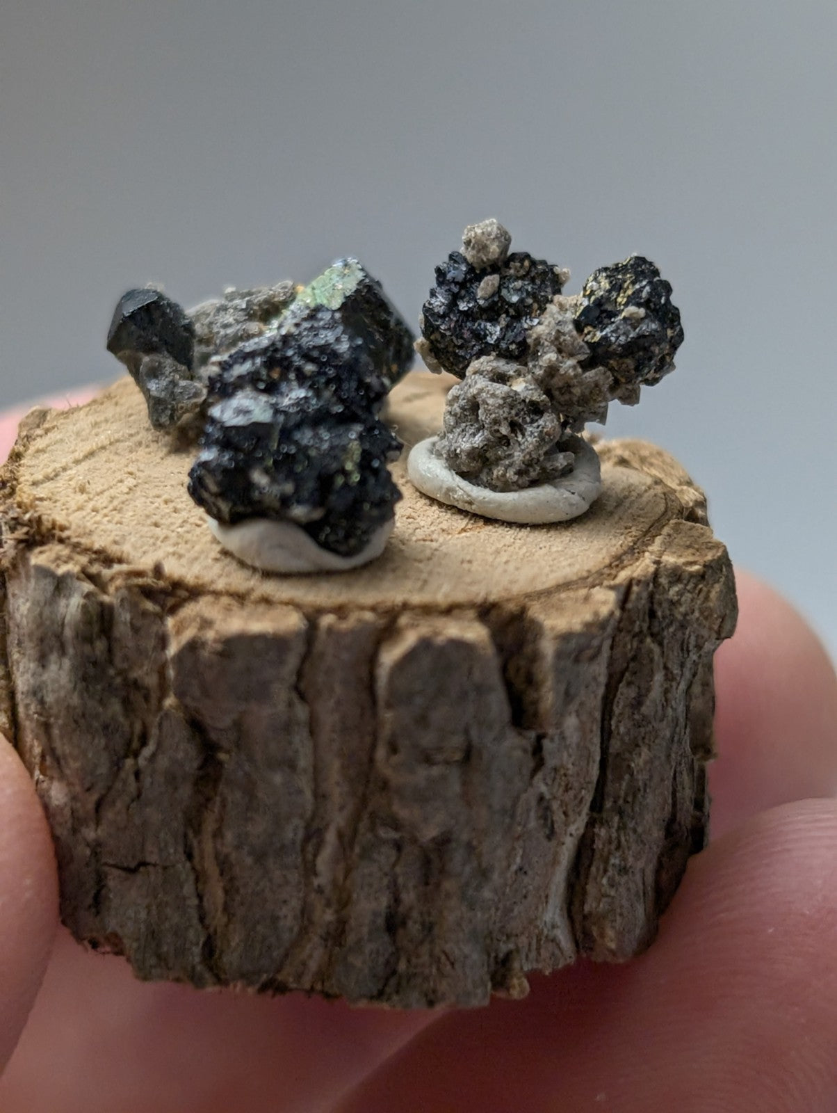 Set of 3 brookite and smoky quartz mineral specimens with dark glossy green and black surfaces on wood stand