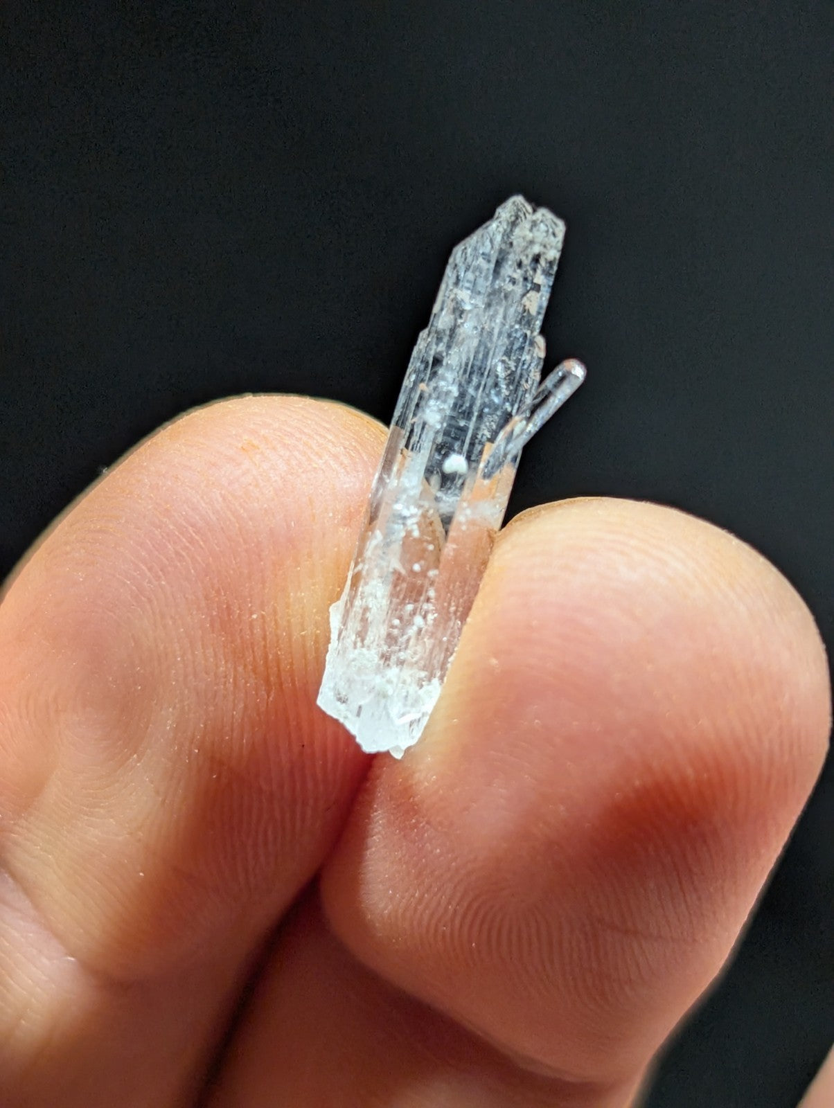A translucent, clear quartz crystal with a pointed tip and visible internal striations.