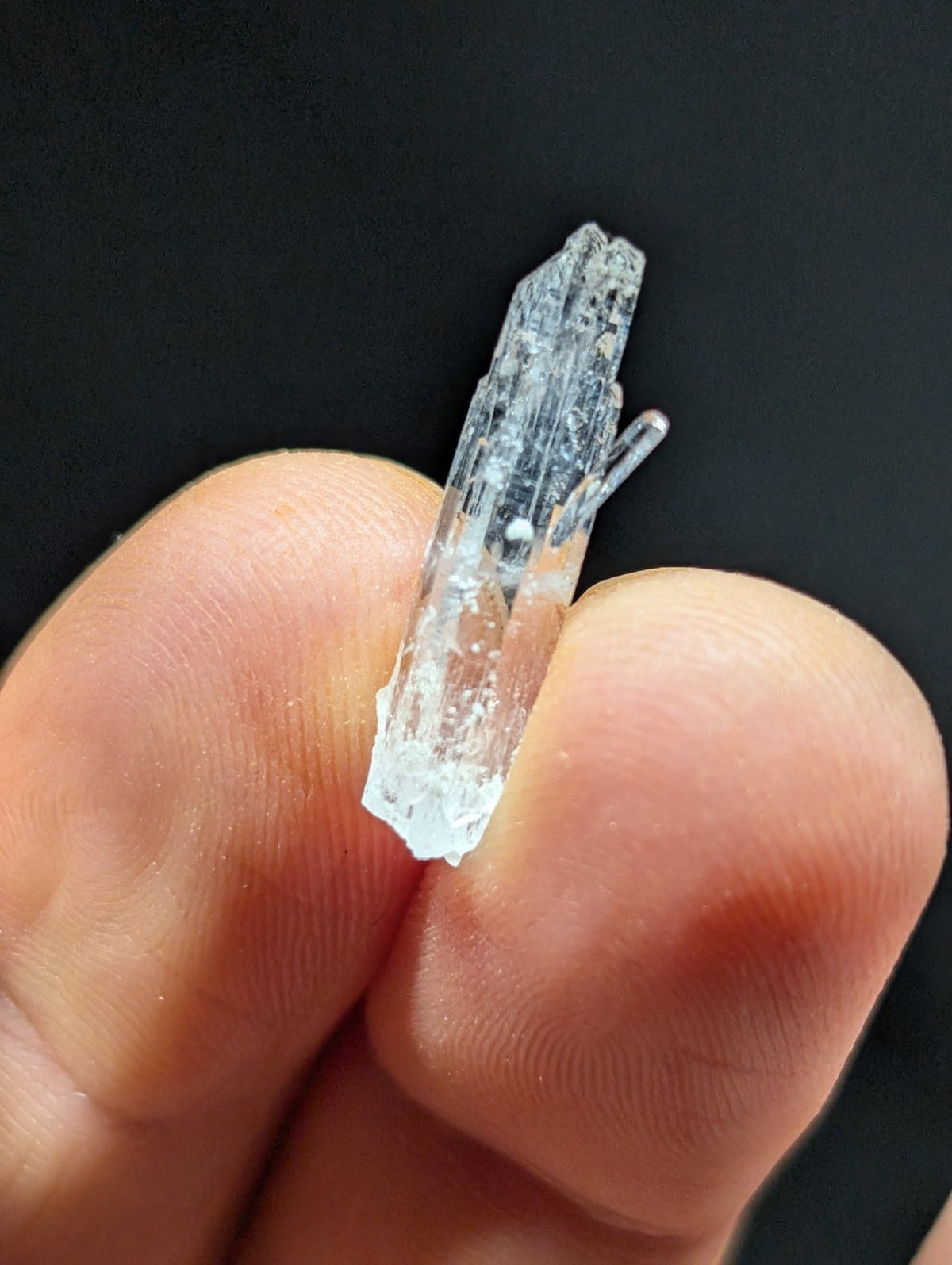 A translucent, clear quartz crystal with a pointed tip and visible internal striations.