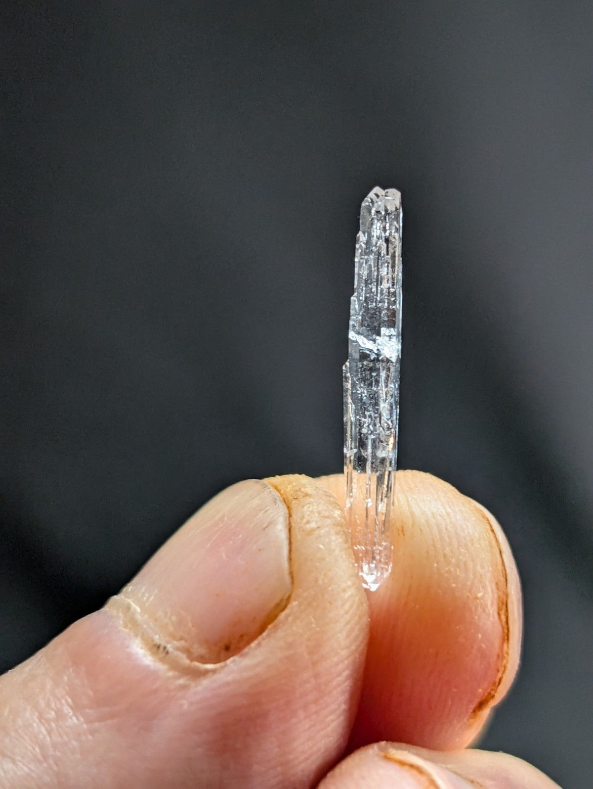 A clear, translucent quartz crystal with a pointed tip and visible internal striations.