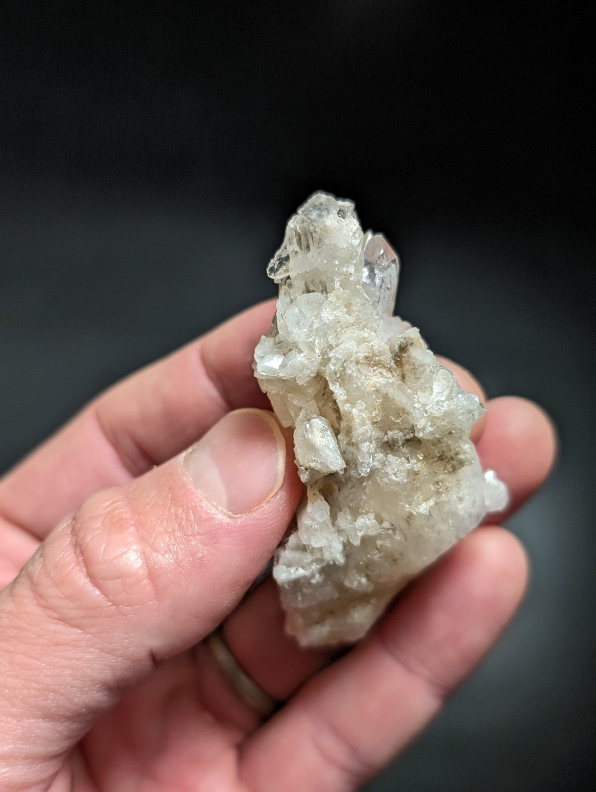 A translucent, crystalline quartz cluster with clear and milky white facets held in a hand.