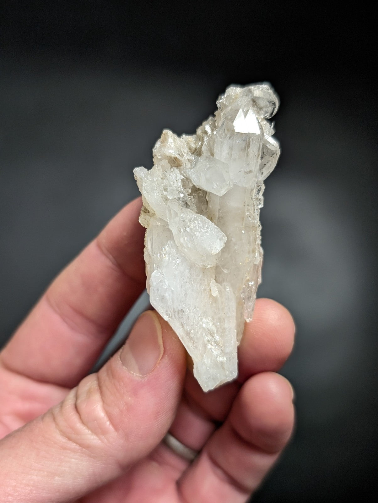 A translucent, clear quartz crystal cluster with a rough, jagged surface and pointed terminations.