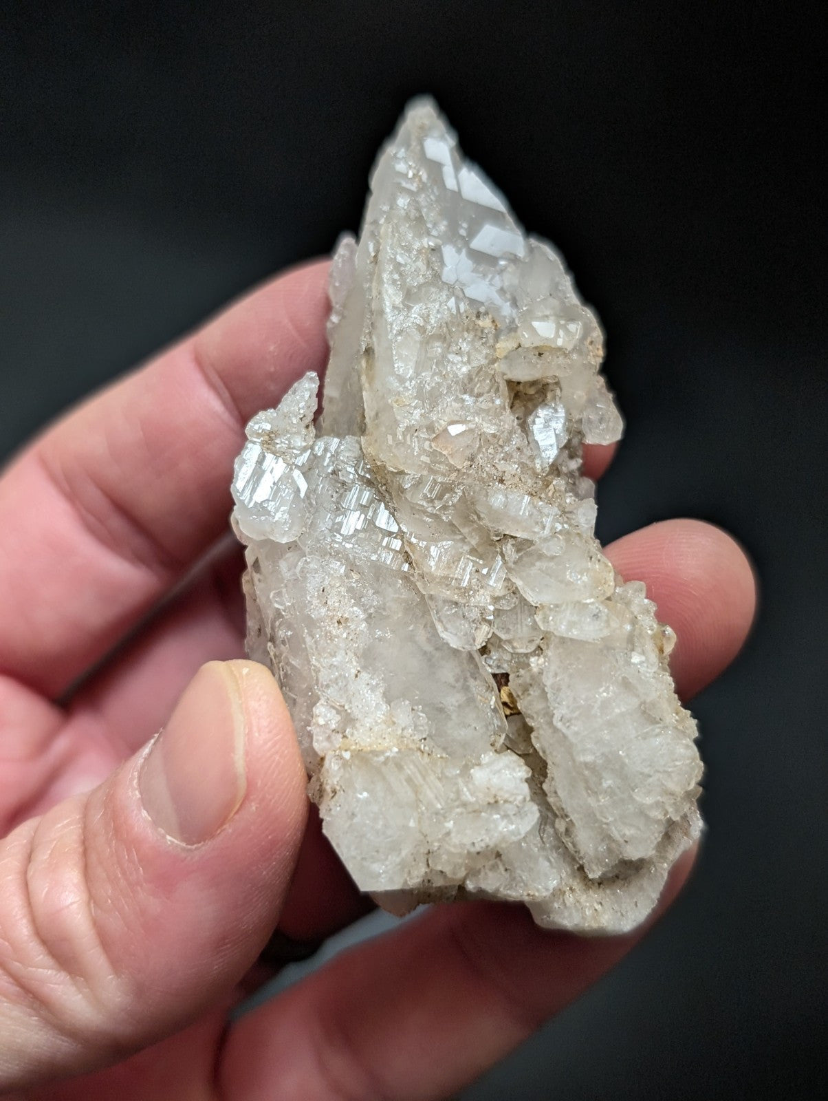 A translucent, crystalline quartz cluster with sharp, faceted points and a pale, milky white hue.