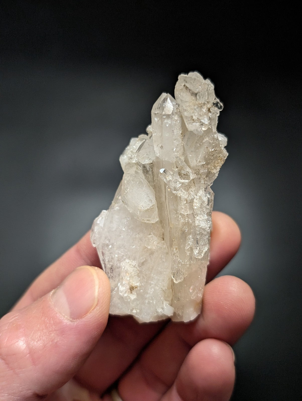 A translucent, clear quartz crystal cluster with sharp, pointed facets and a slightly rough, natural texture.