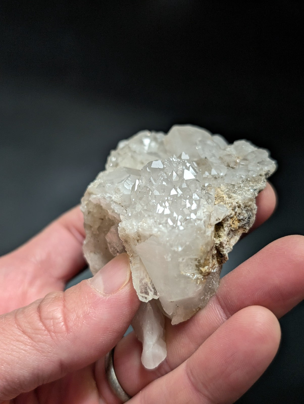 A translucent white quartz crystal cluster with sharp, faceted points and a rough, earthy base.