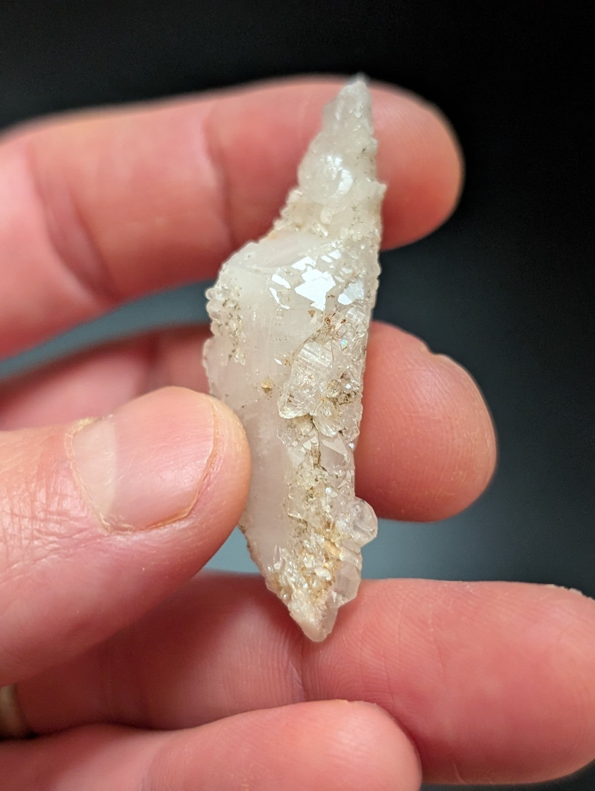 A translucent white quartz crystal cluster with a rough, jagged surface and embedded golden mineral inclusions.