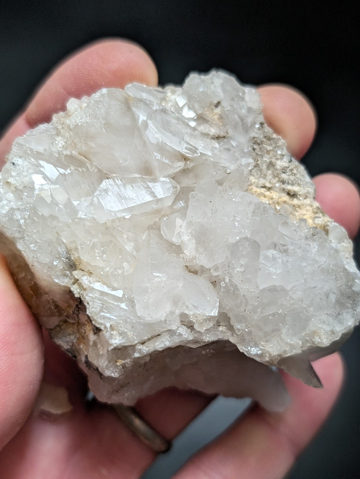 A translucent white quartz crystal cluster with sharp, faceted points and a rough, earthy base.